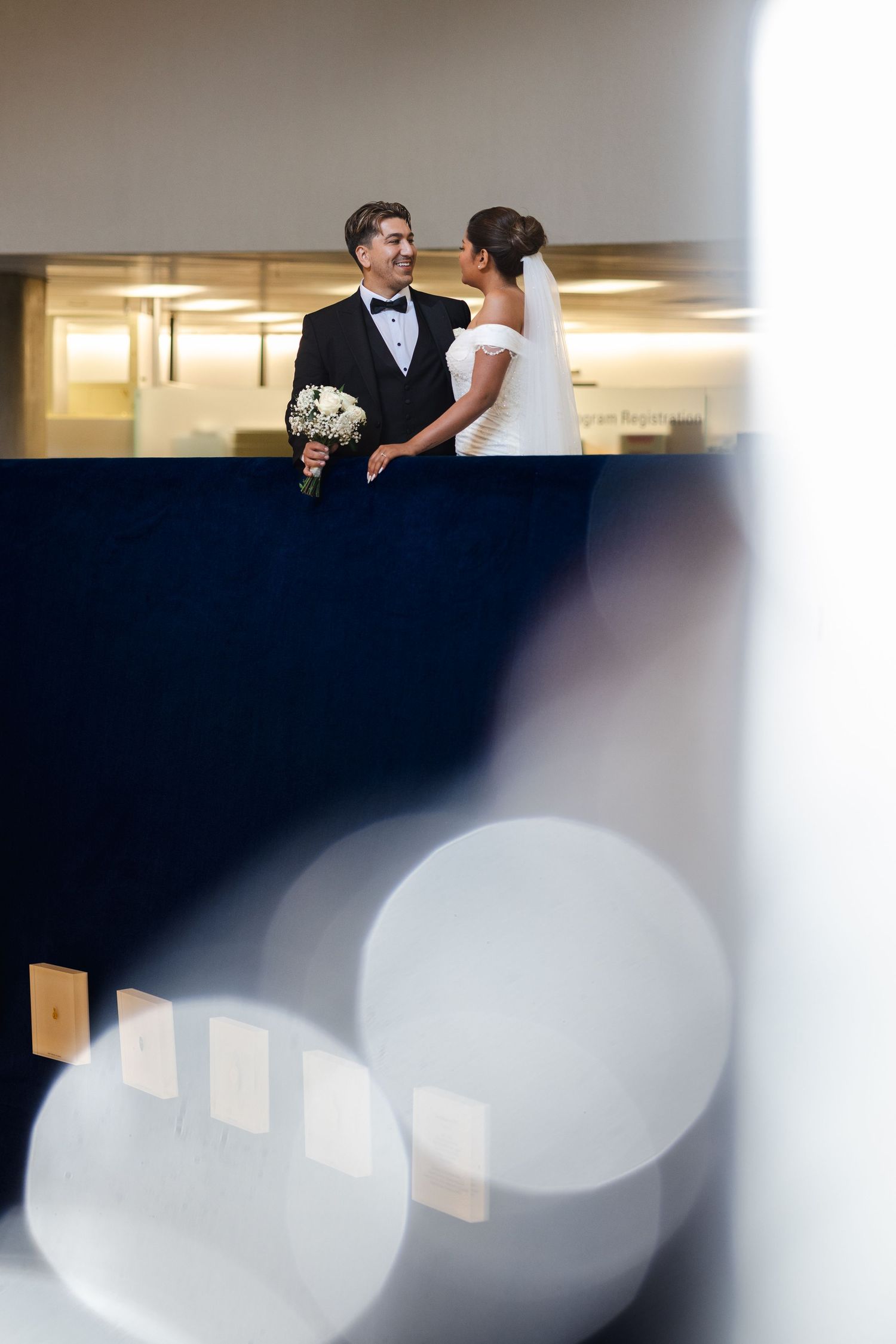 Elegant wedding couple shares an intimate moment during their reception in a modern, minimalist venue with soft lighting.