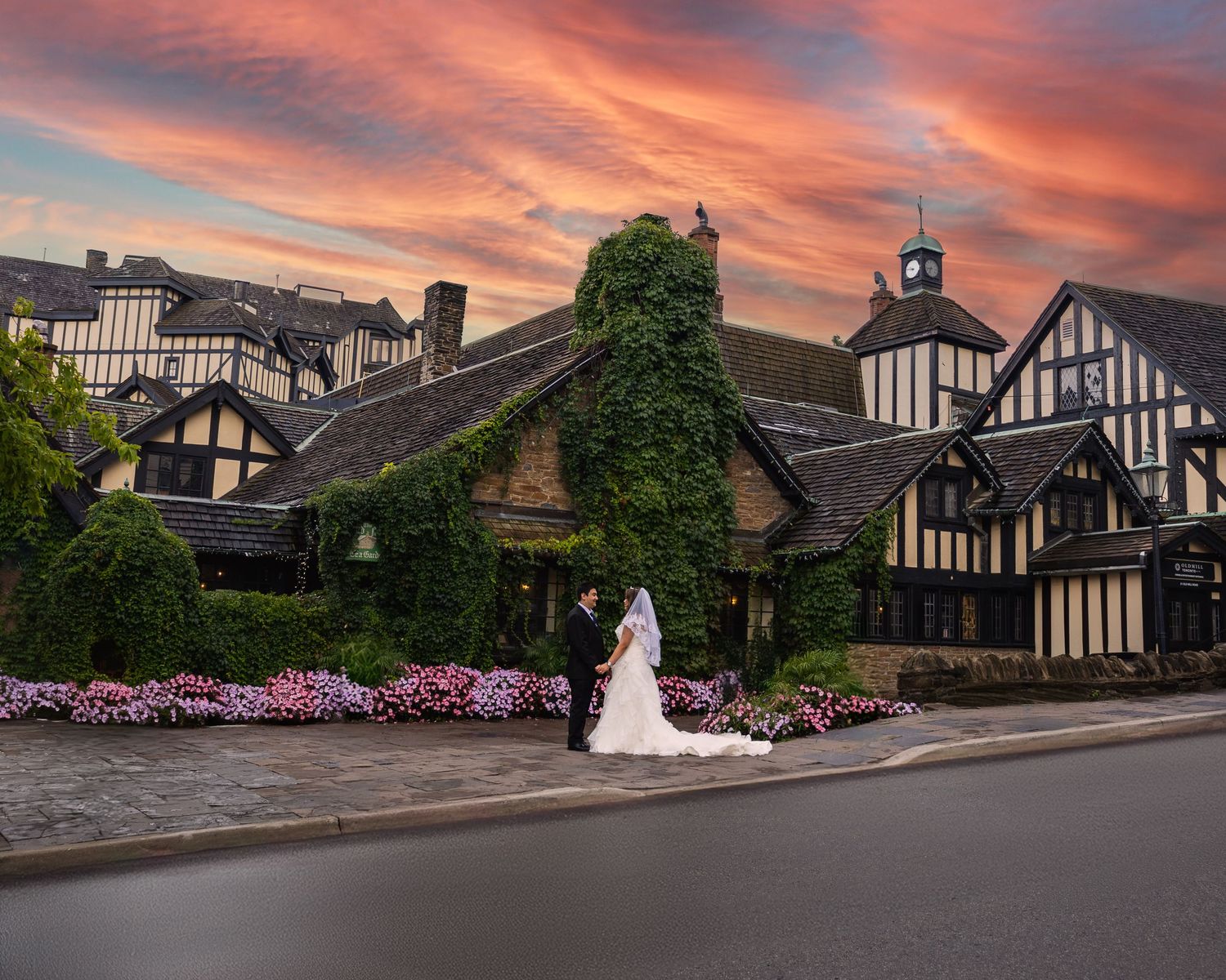 Tudor-style mansion with ivy-covered walls and vibrant sunset sky creates a romantic setting at dusk.