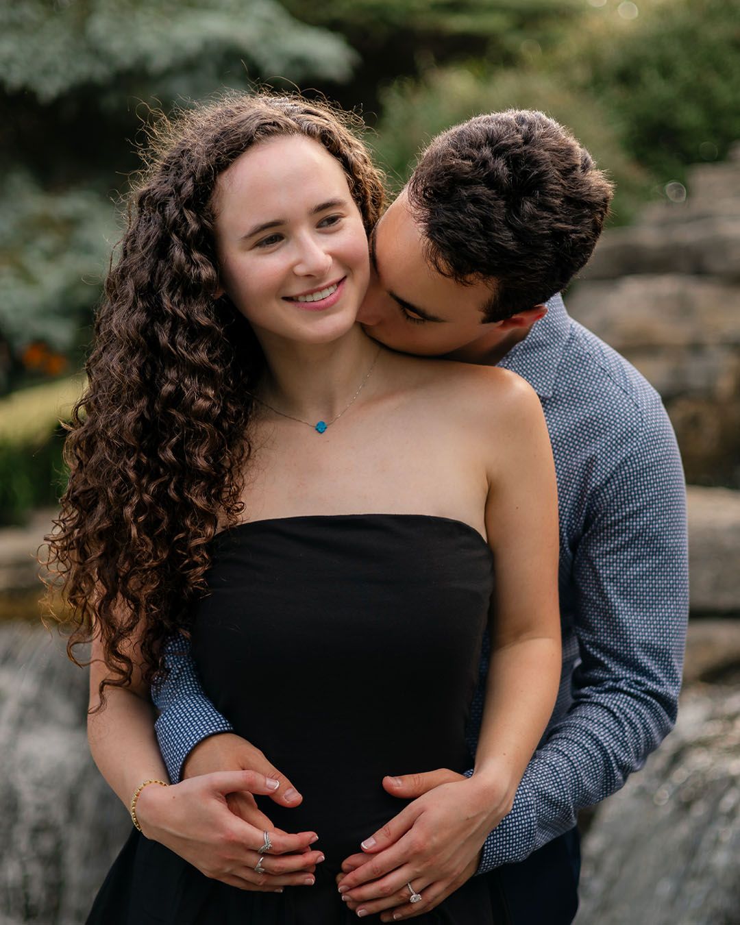 Romantic couple shares tender moments in nature with embraces and laughter during an intimate engagement photo session.