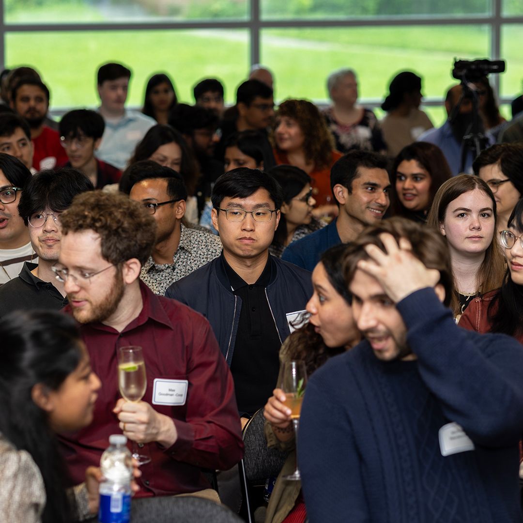 Diverse group of young professionals attending a networking reception event, some holding champagne glasses.