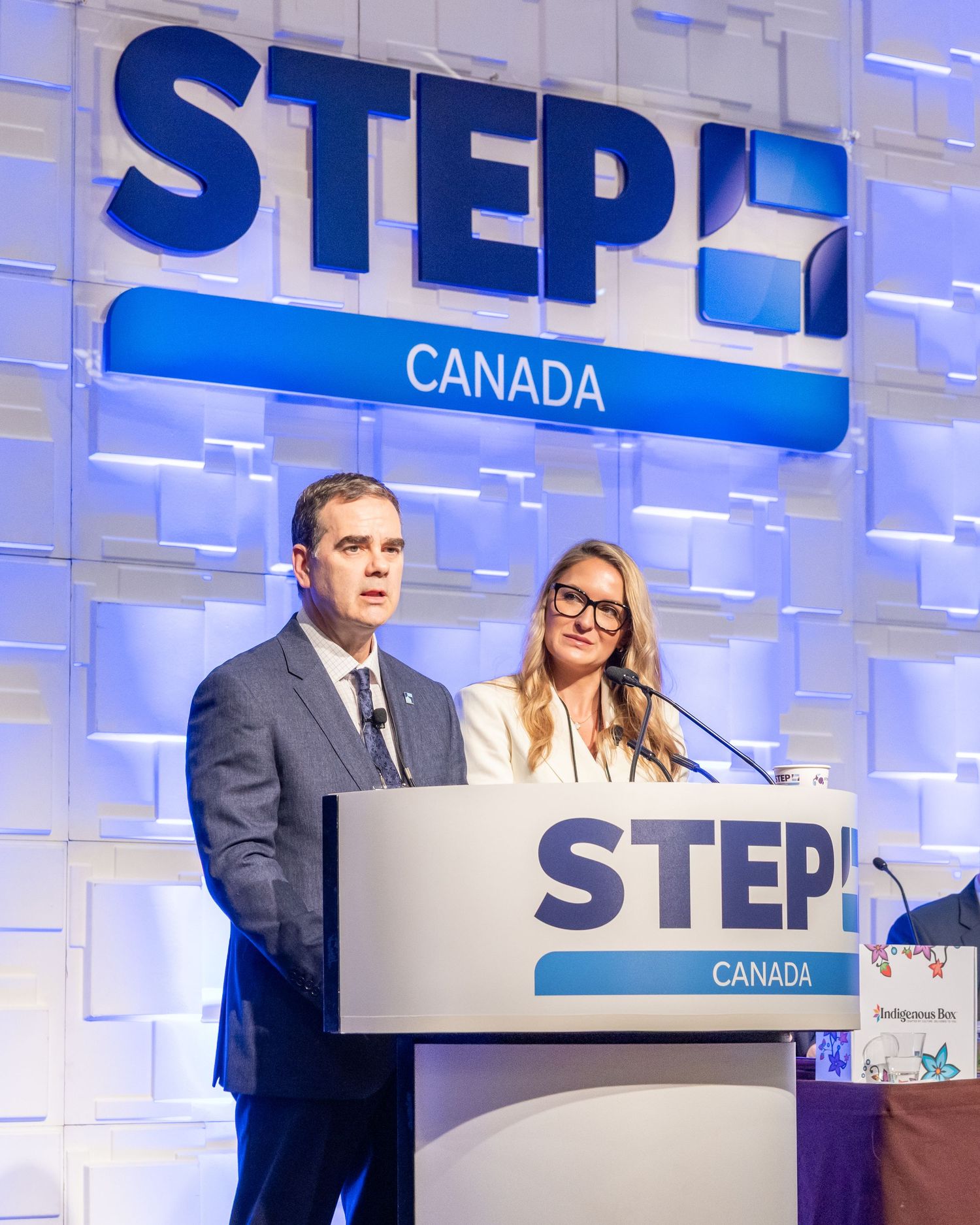 Two speakers present at a STEP Canada conference podium during a professional event.