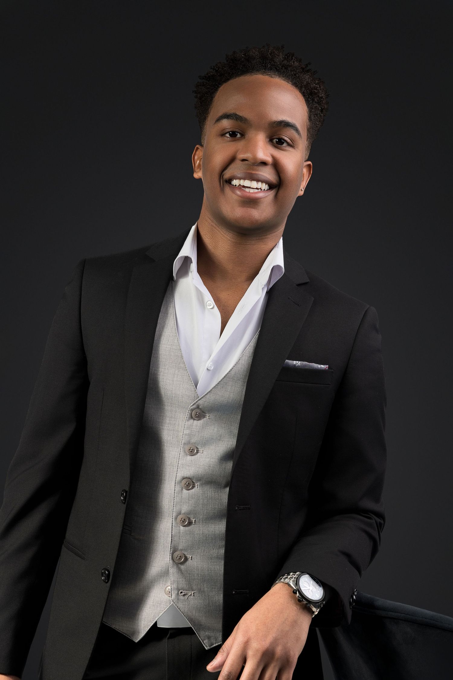 Professional portrait series of person wearing formal black suit and white vest against dark background with warm lighting.