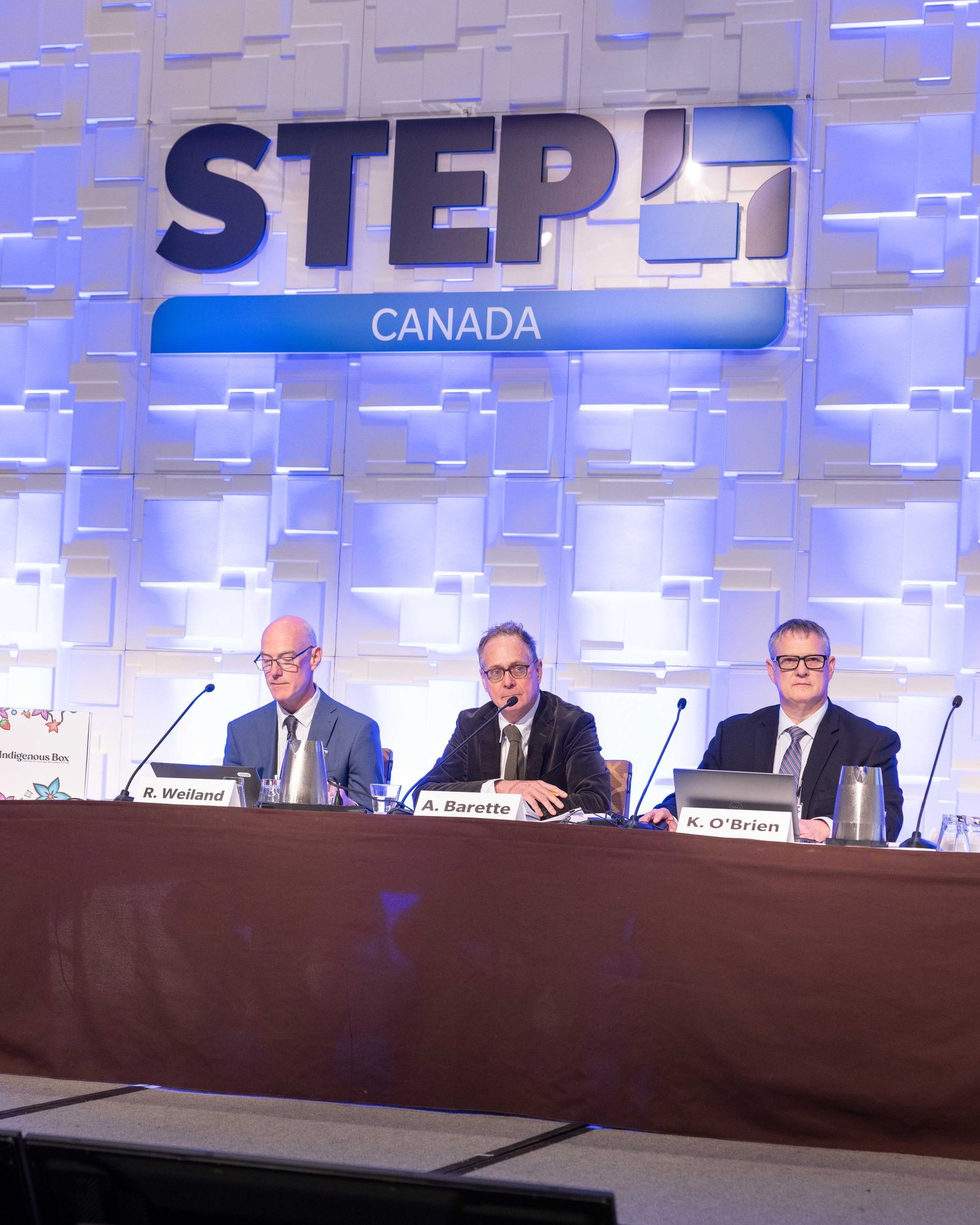 Three professionals seated at a panel table at STEP Canada conference, with name placards visible.