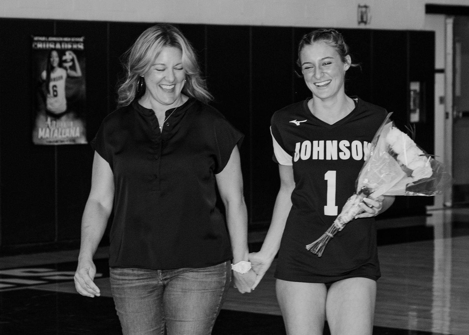 A mother and daughter sharing a moment at a volleyball senior night in a school gymnasium.