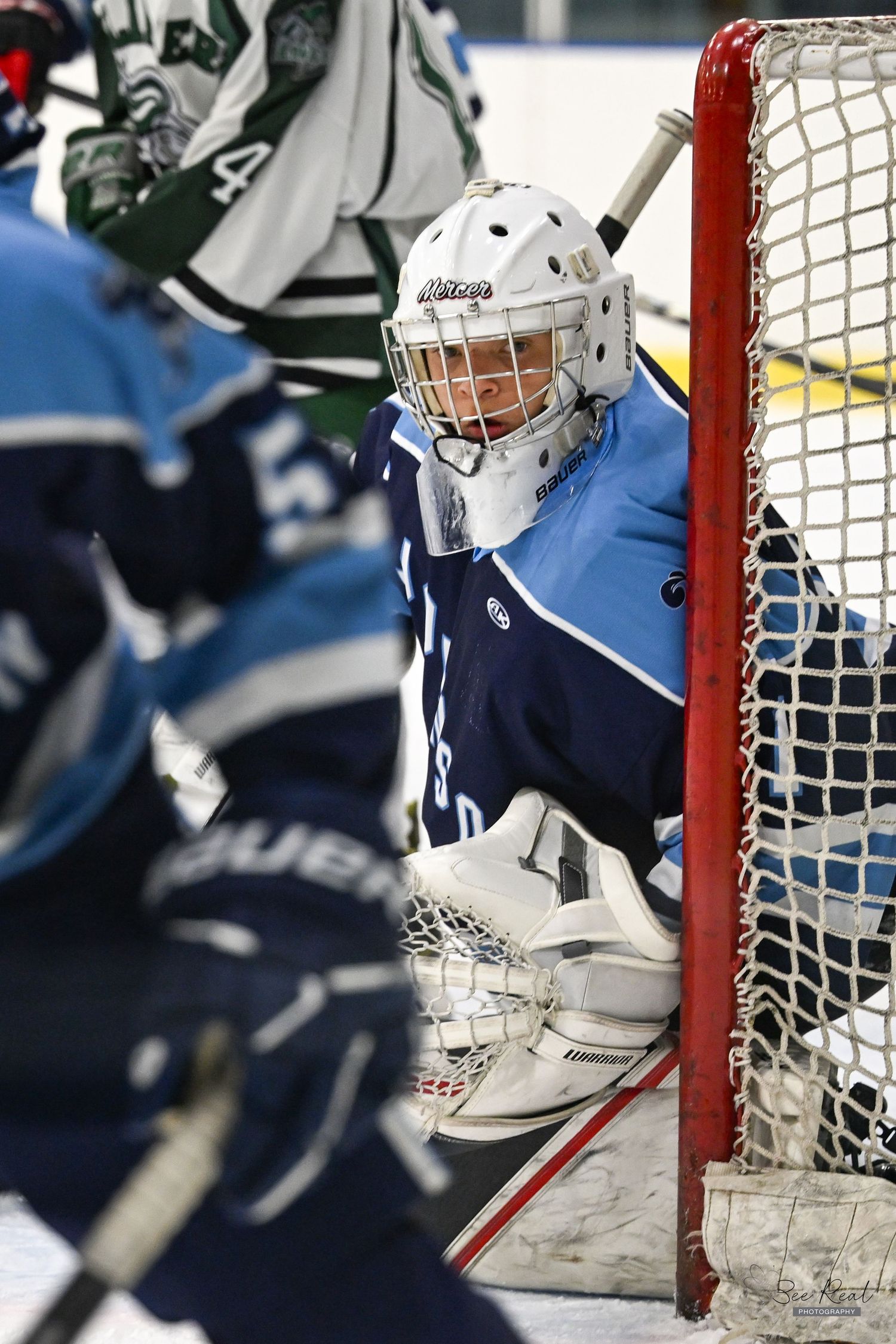 A hockey goalie crouches in front of the net during an intense game.