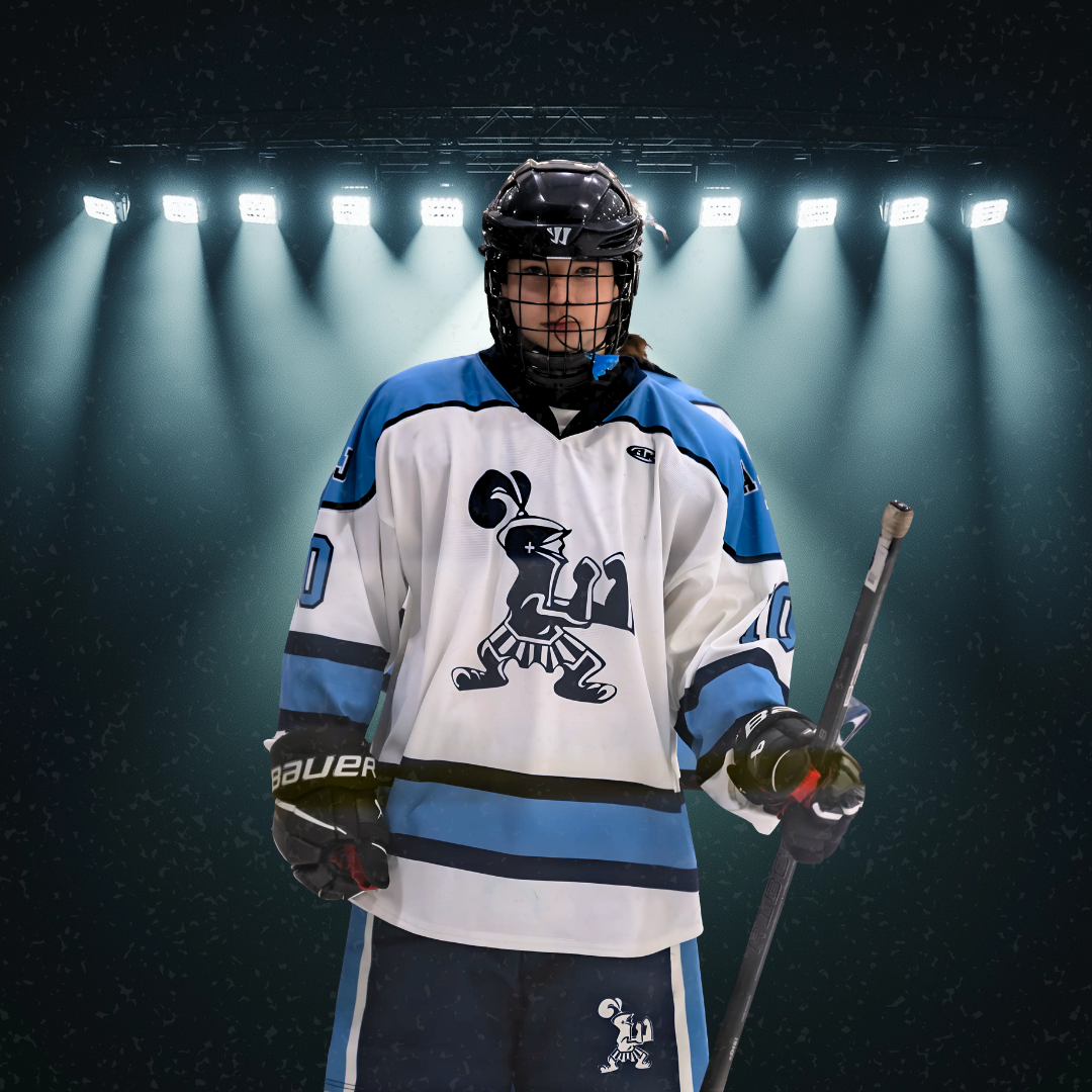 Hockey player in white and blue uniform poses dramatically under spotlight array.