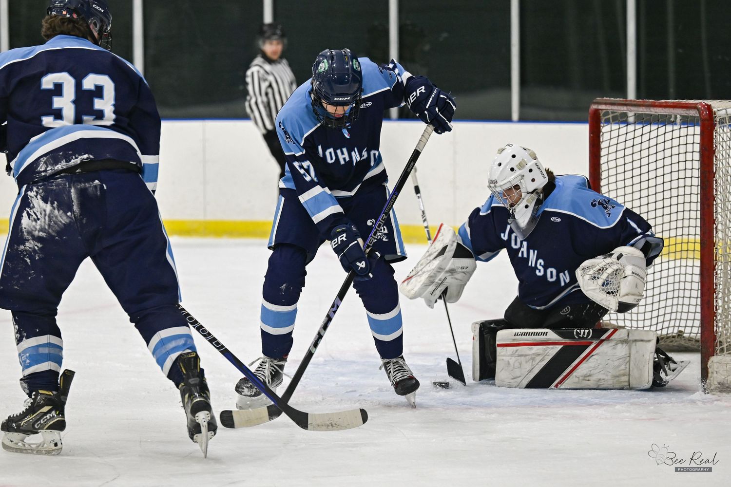 Ice hockey players compete for the puck during an intense game with players in dark and light jerseys.