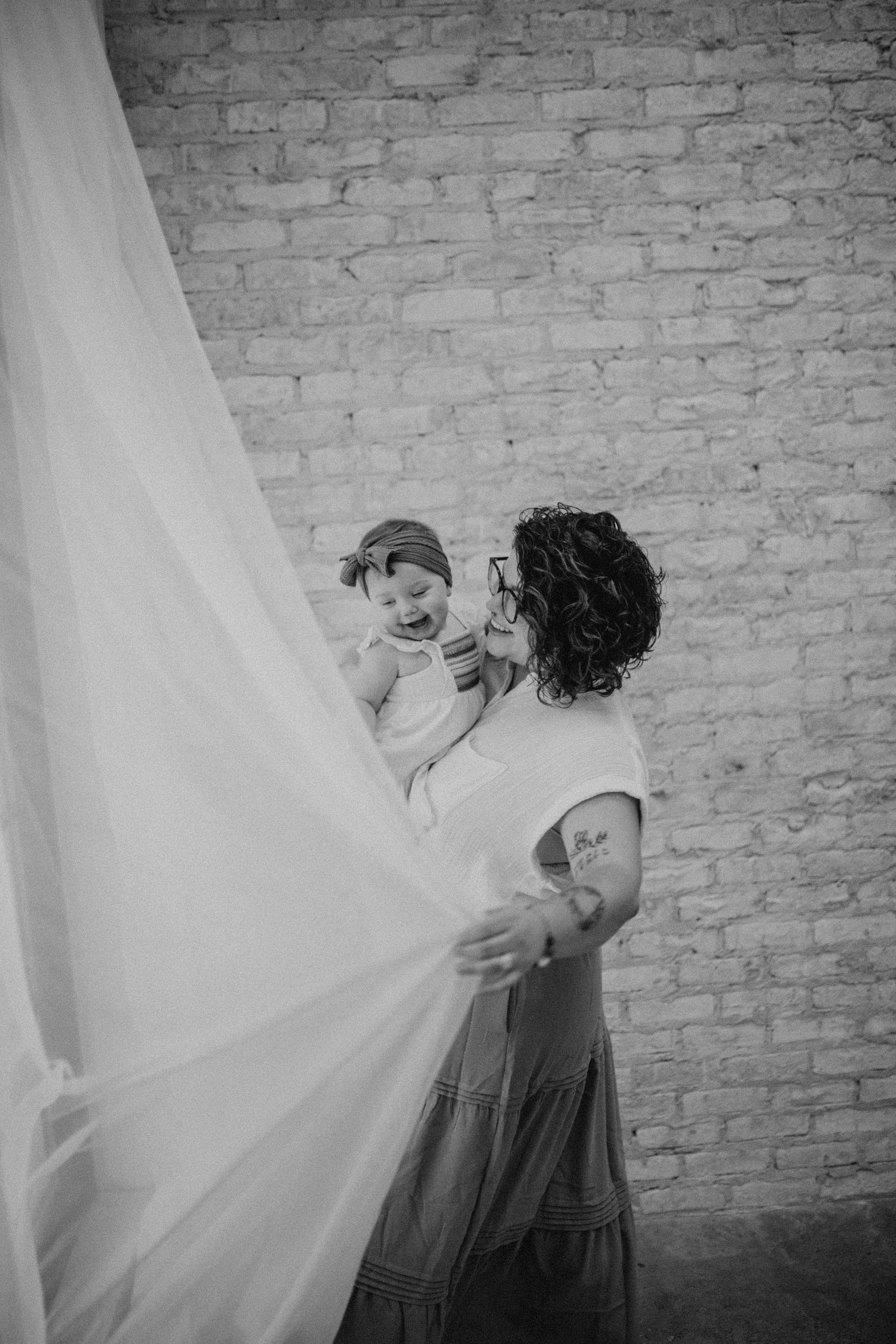 Artistic sequence showing movement with white fabric against textured brick wall.