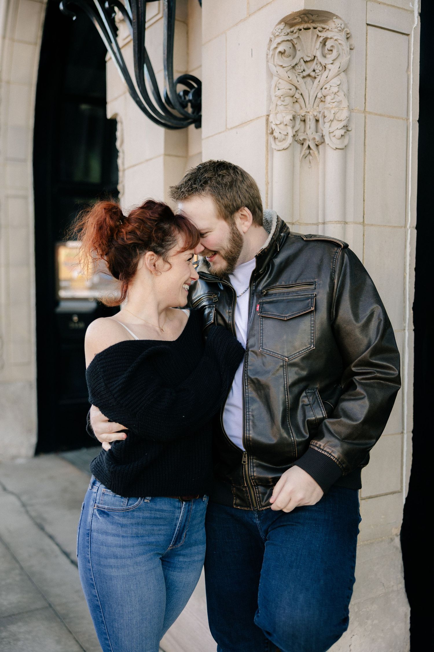 Candid couple shares romantic moment against ornate architectural backdrop.