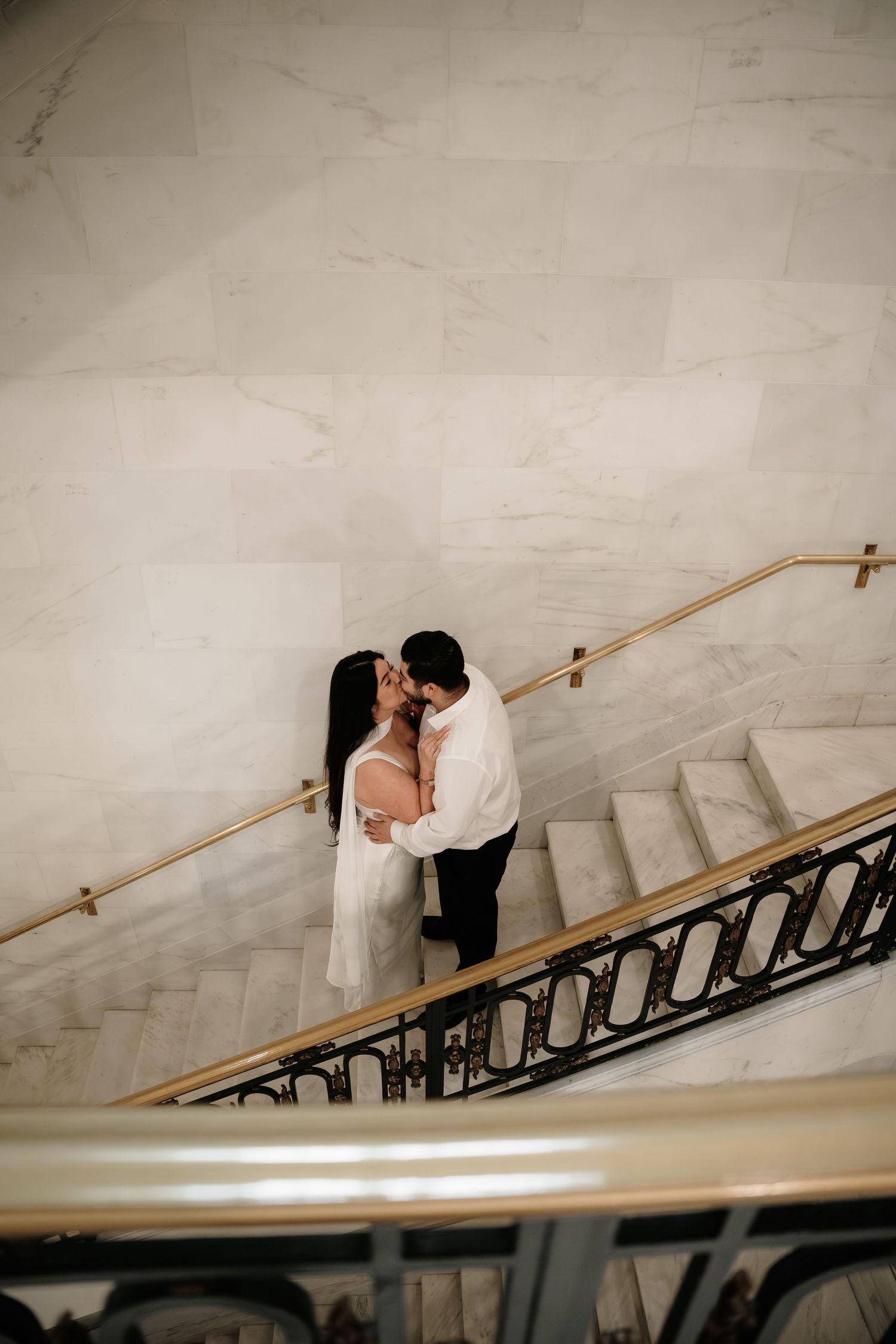 A couple in wedding attire share an intimate moment on a grand marble staircase in a sequence of romantic photos.