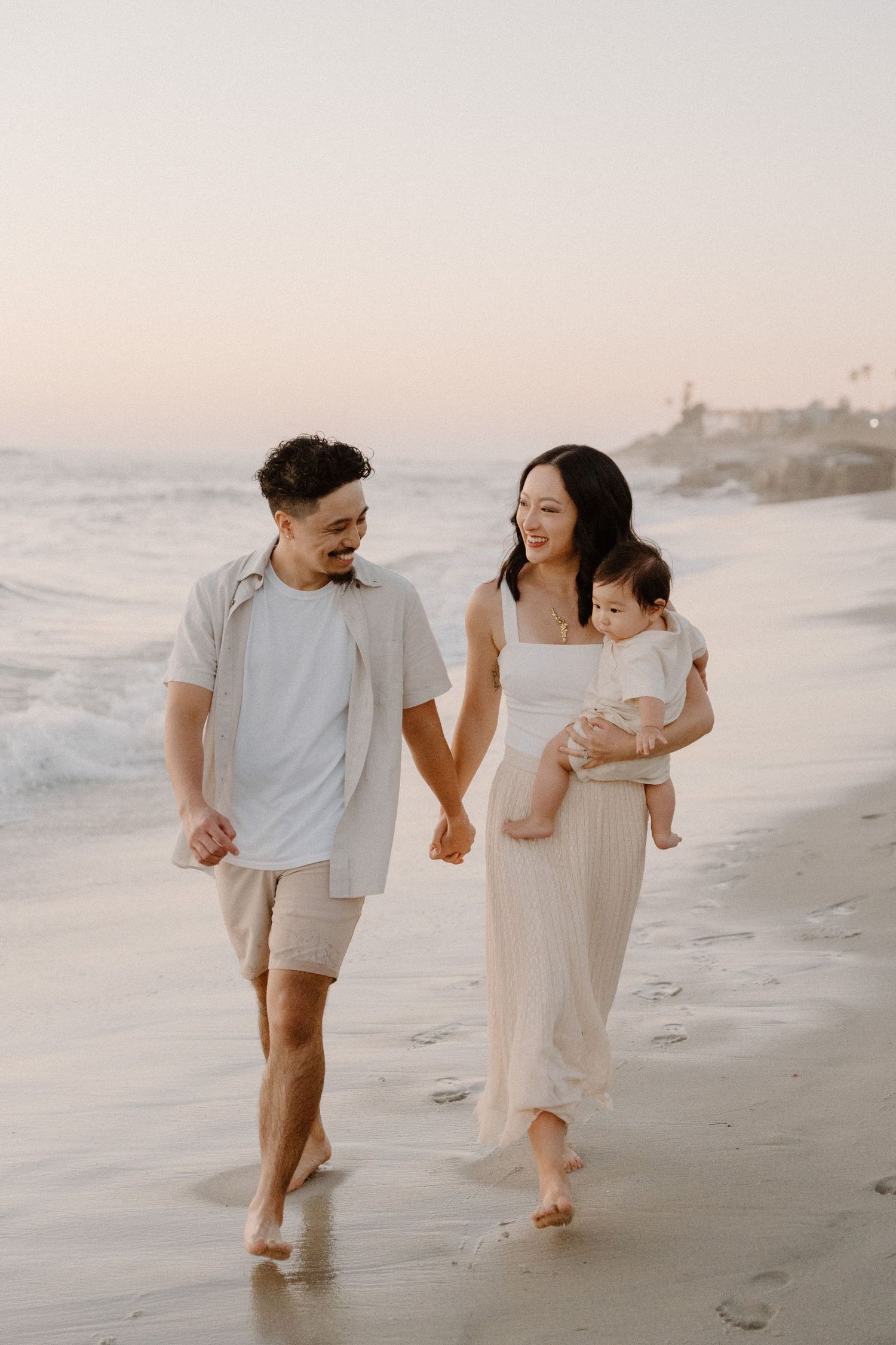 Happy family walking along beach at sunset holding hands  in La Jolla in San Diego, CA.