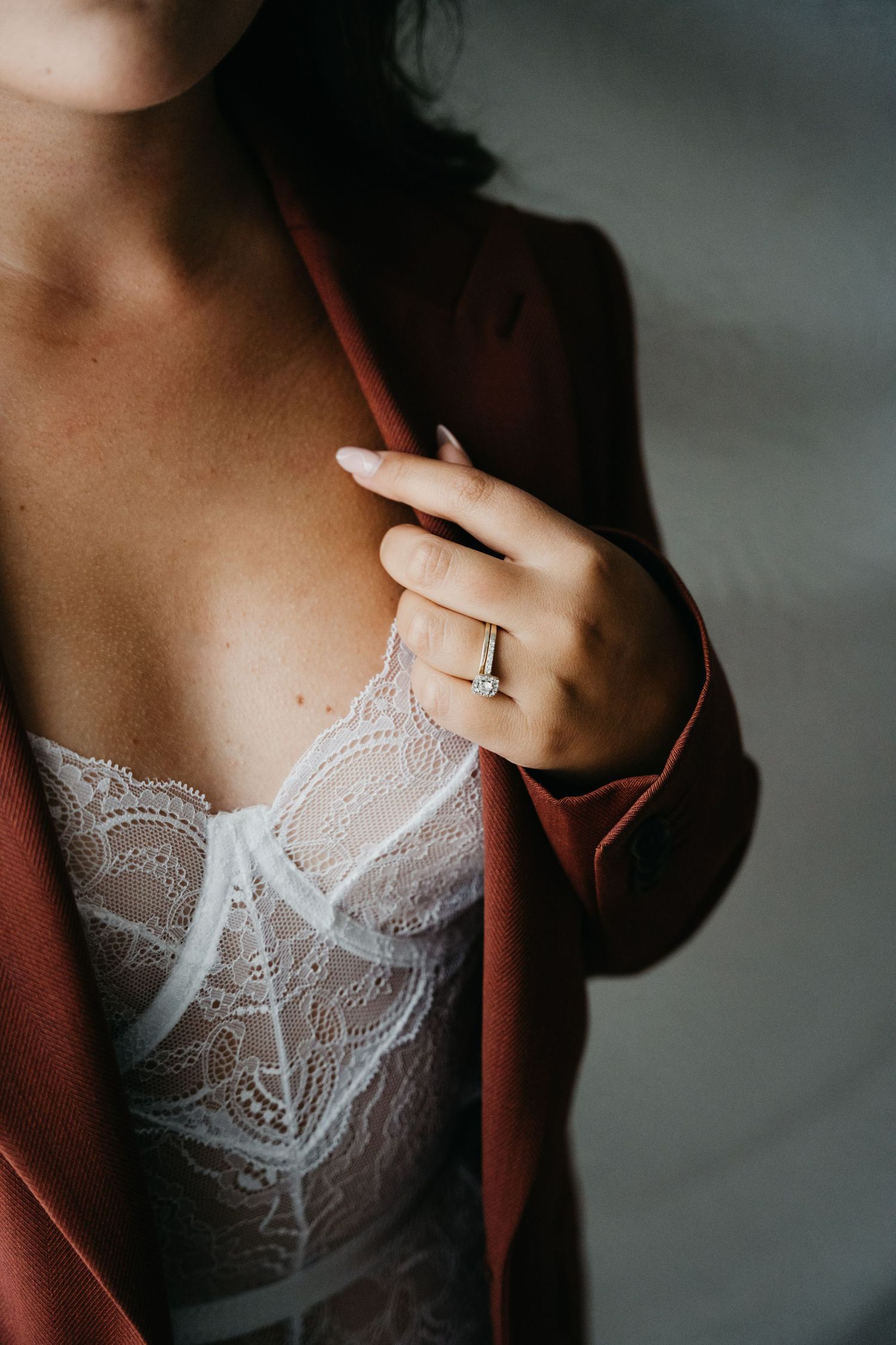 Close-up photo of lace lingerie and engagement ring with burgundy robe.