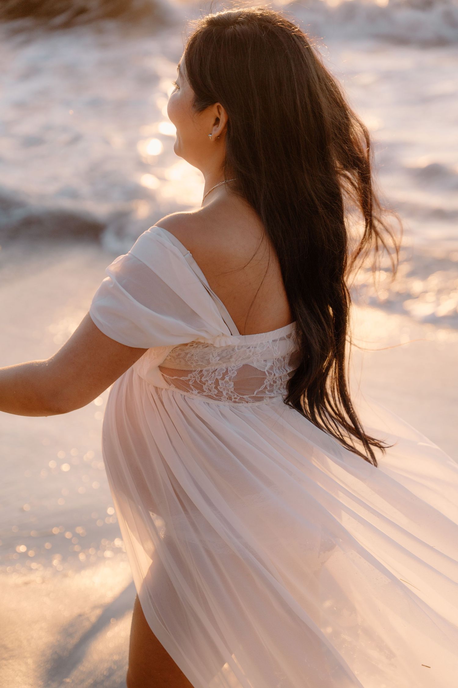 Ethereal beach portrait of woman in flowing white dress at sunset  in La Jolla in San Diego, CA.