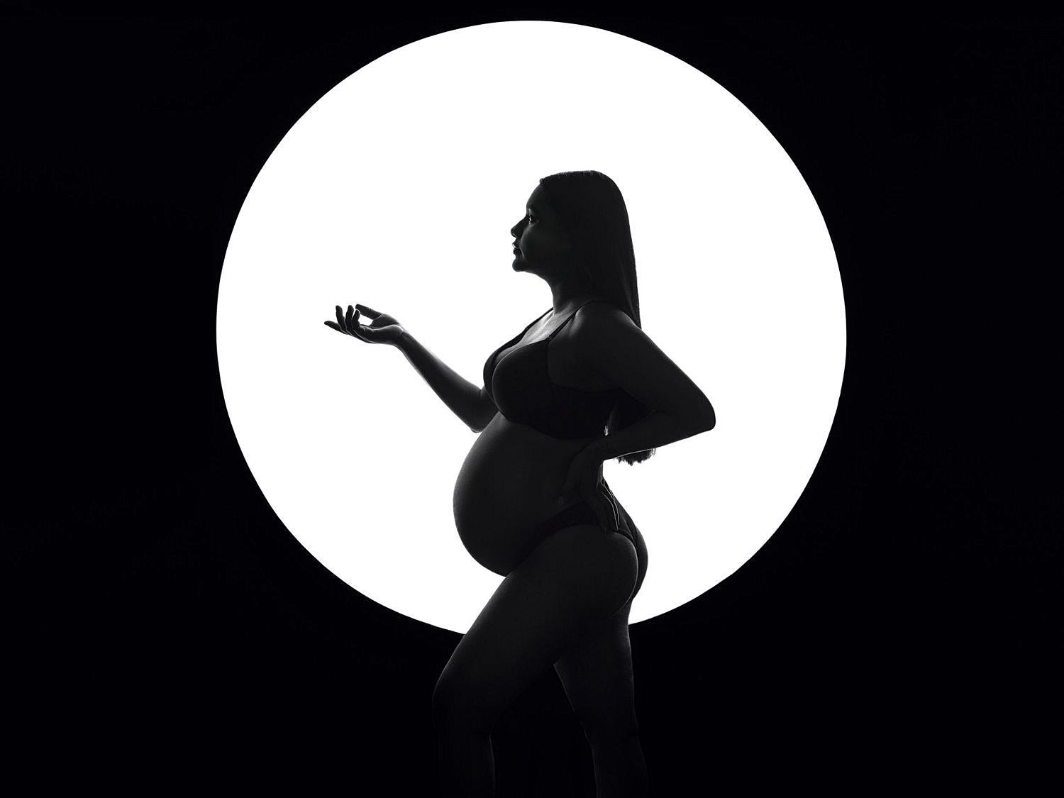 High contrast silhouettes of pregnant figure in white ovals against black background.