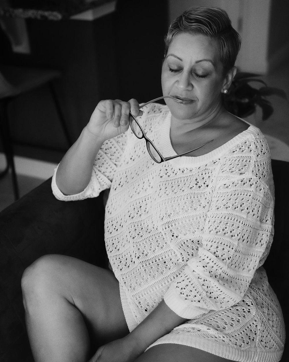 Black and white portrait of someone wearing a delicate lace sweater in a contemplative pose.