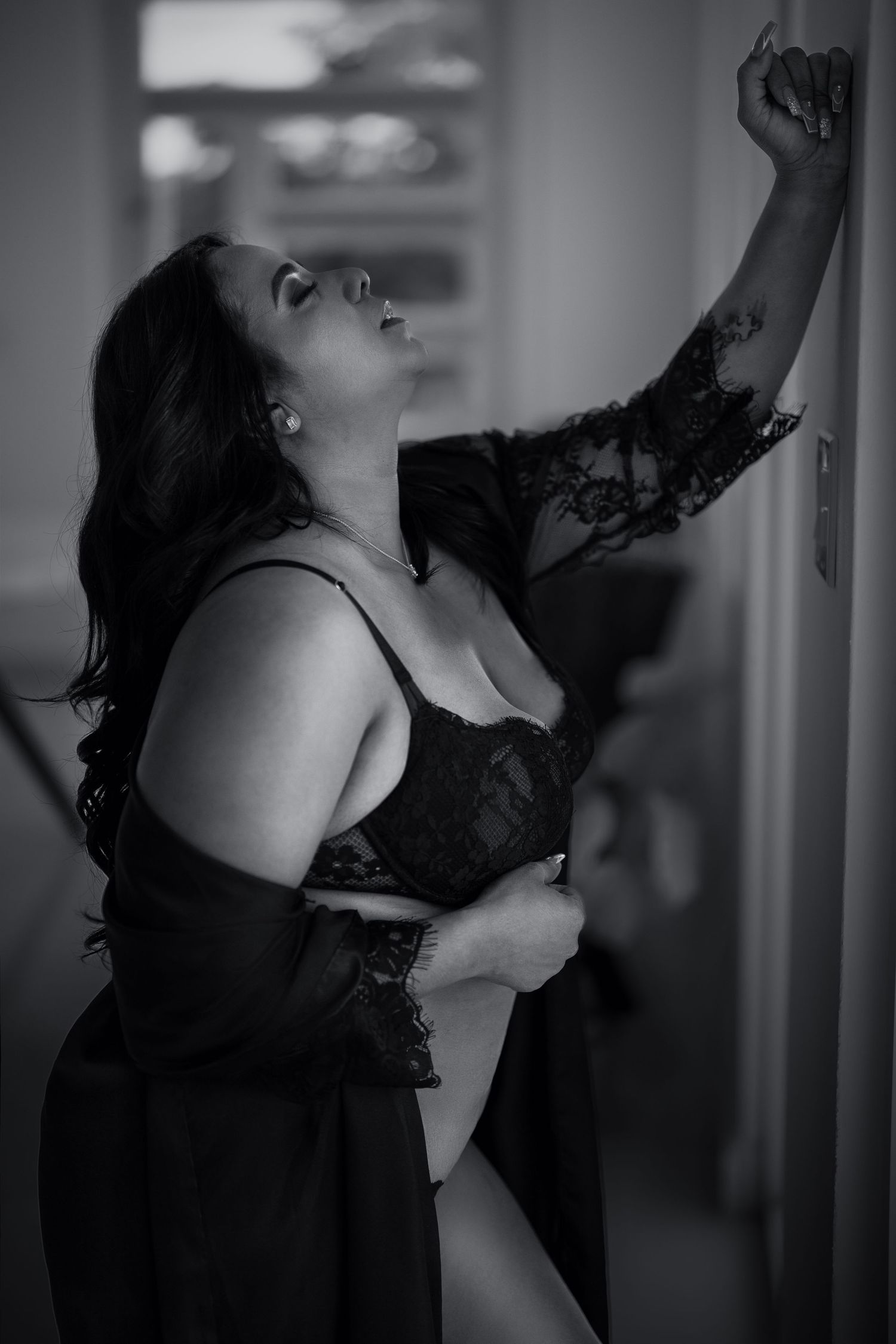 Dramatic black and white boudoir photos showing artistic poses against a wall.