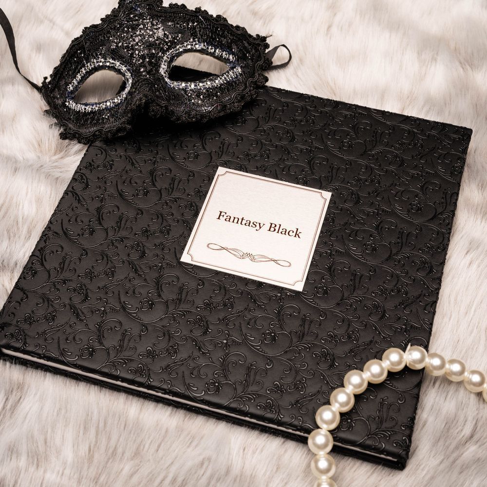 Elegant Fantasy Black embossed guest book with pearl necklace and black masquerade mask on white fur background.