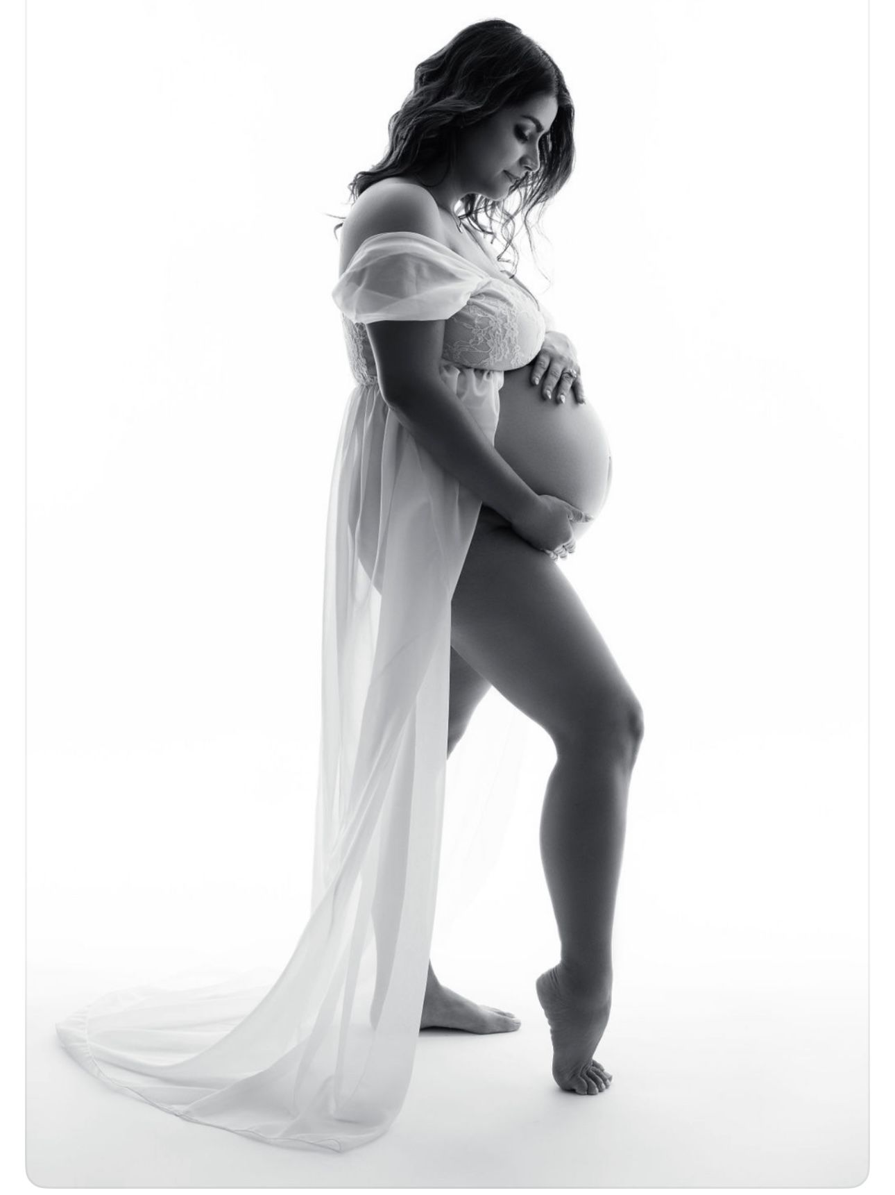 A series of artistic black and white maternity photos showing a pregnant woman in flowing white fabric against white backdrop.