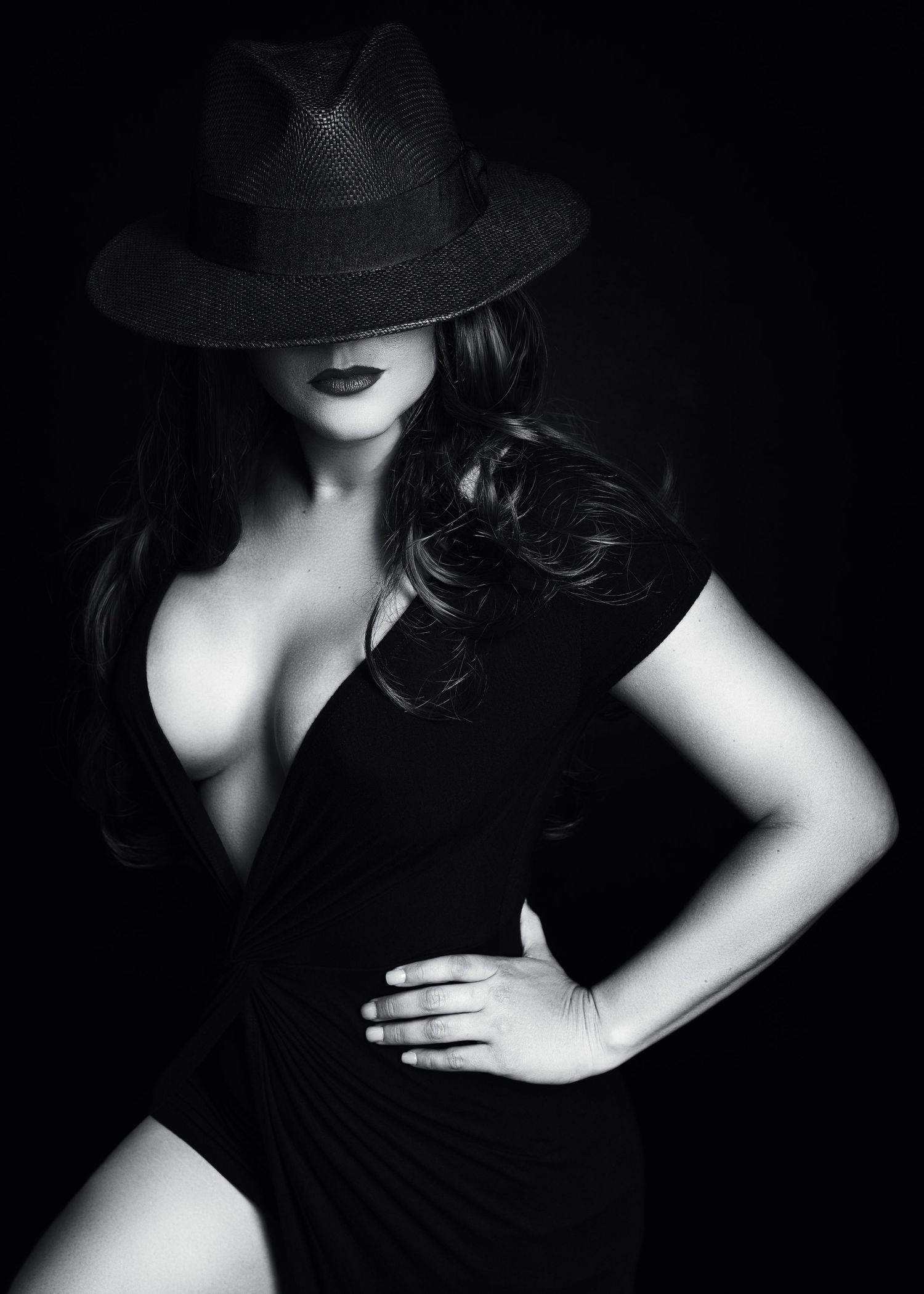 Film noir style portrait in black and white featuring fedora hat and dramatic lighting.