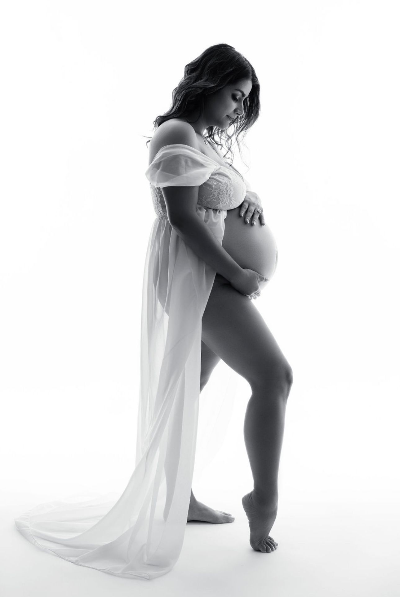 High-key maternity photos with flowing white fabric creating minimalist artistic composition.
