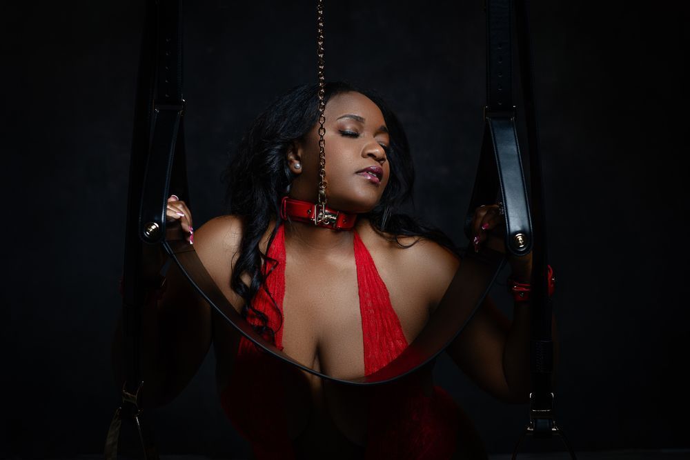 Intimate boudoir photography with red accents and moody lighting.
