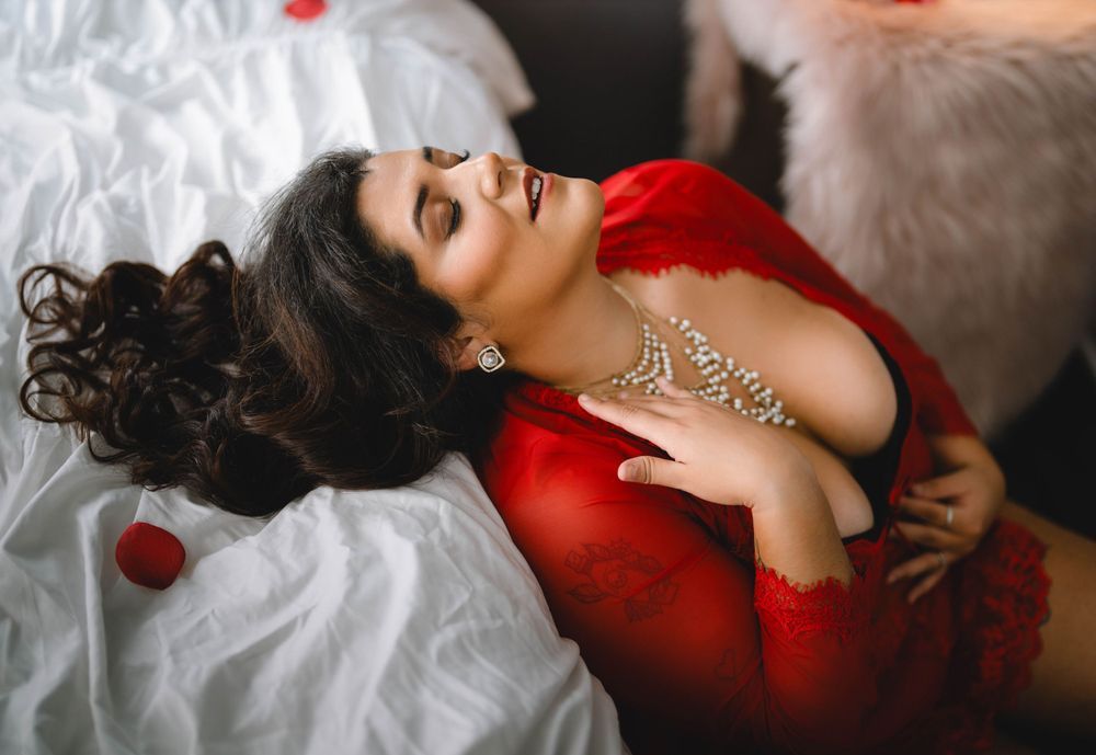 Glamour boudoir photography featuring red lingerie and white fur accents in dramatic lighting.