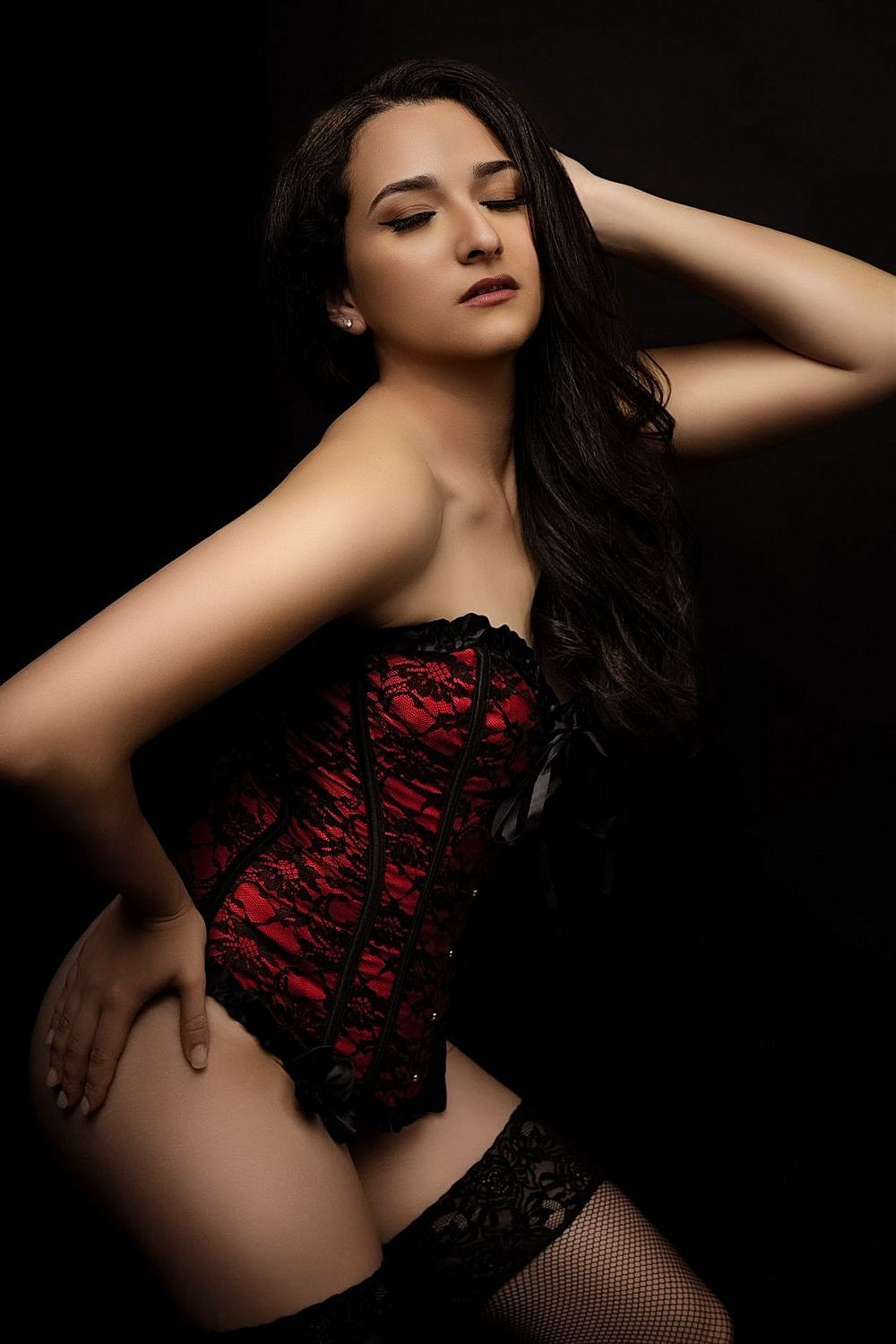 Sensual boudoir photography featuring red lace lingerie against dark background.
