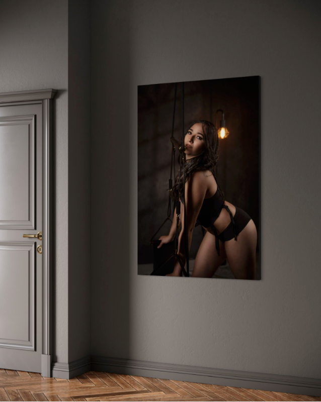 Gallery wall displaying boudoir photographs in elegant grey room with hardwood floors.