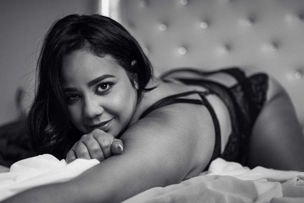 Black and white boudoir photos on tufted headboard bed.