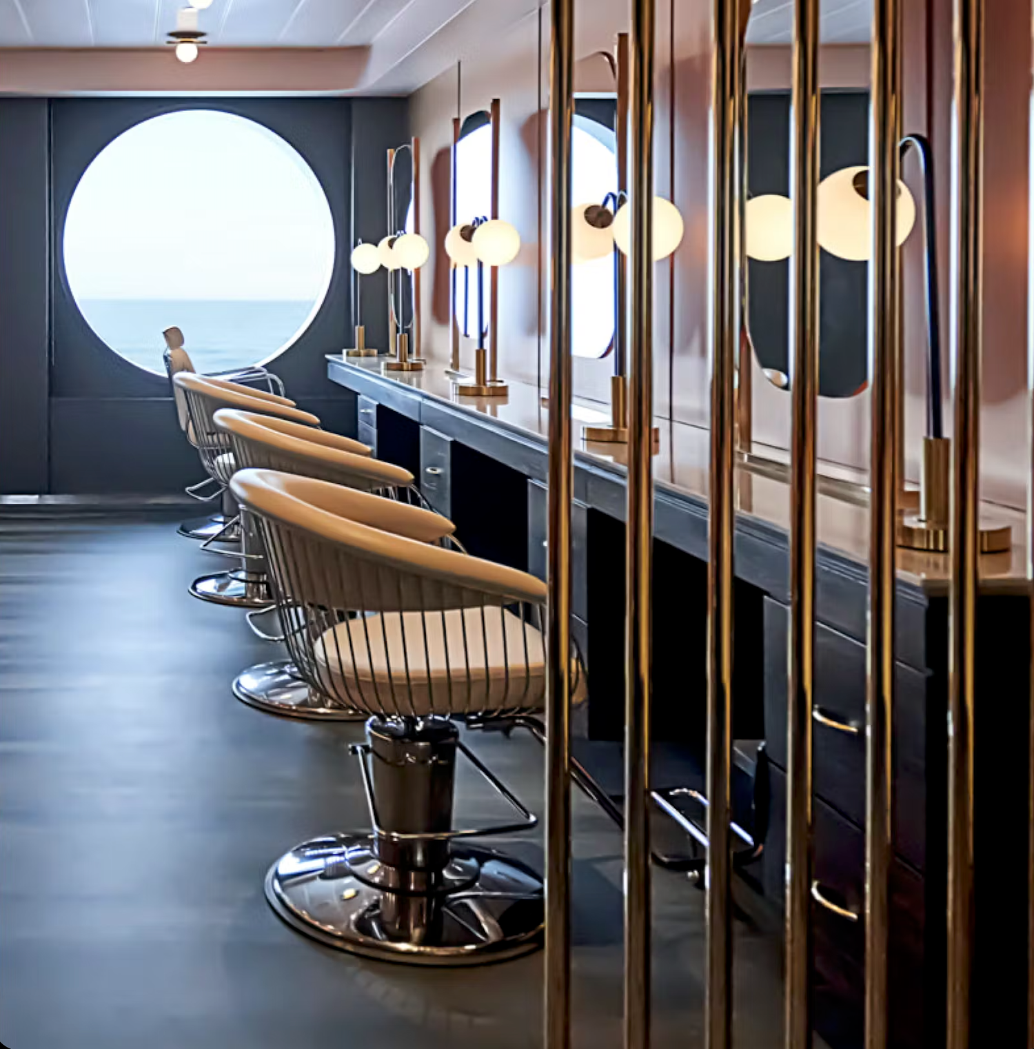 Modern hair salon interior with black walls, chrome barber chairs and dramatic lighting creating an upscale atmosphere.