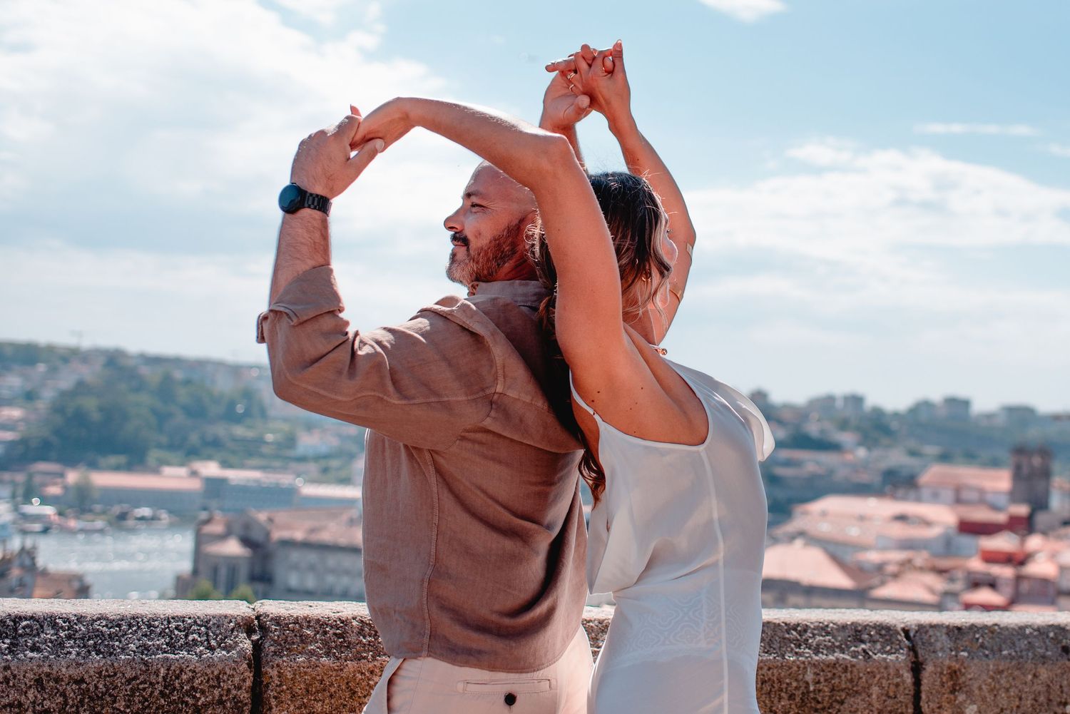 Joyful couple sharing an intimate moment against a sunny city backdrop.