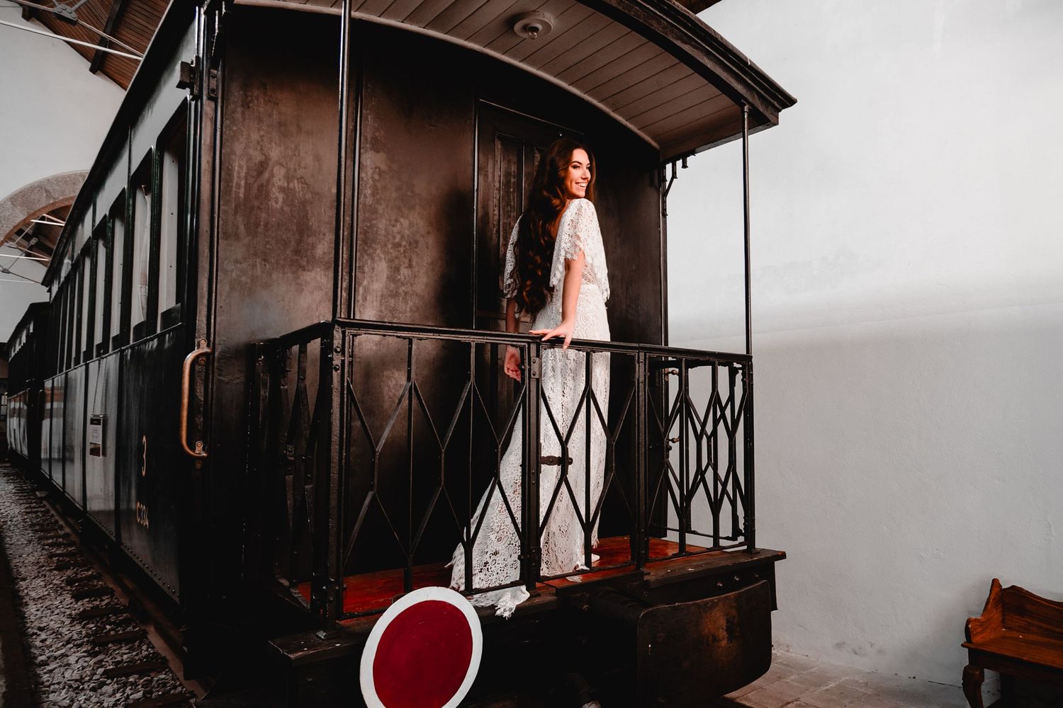 White lace dress contrasts beautifully against vintage train car interior in moody lighting.