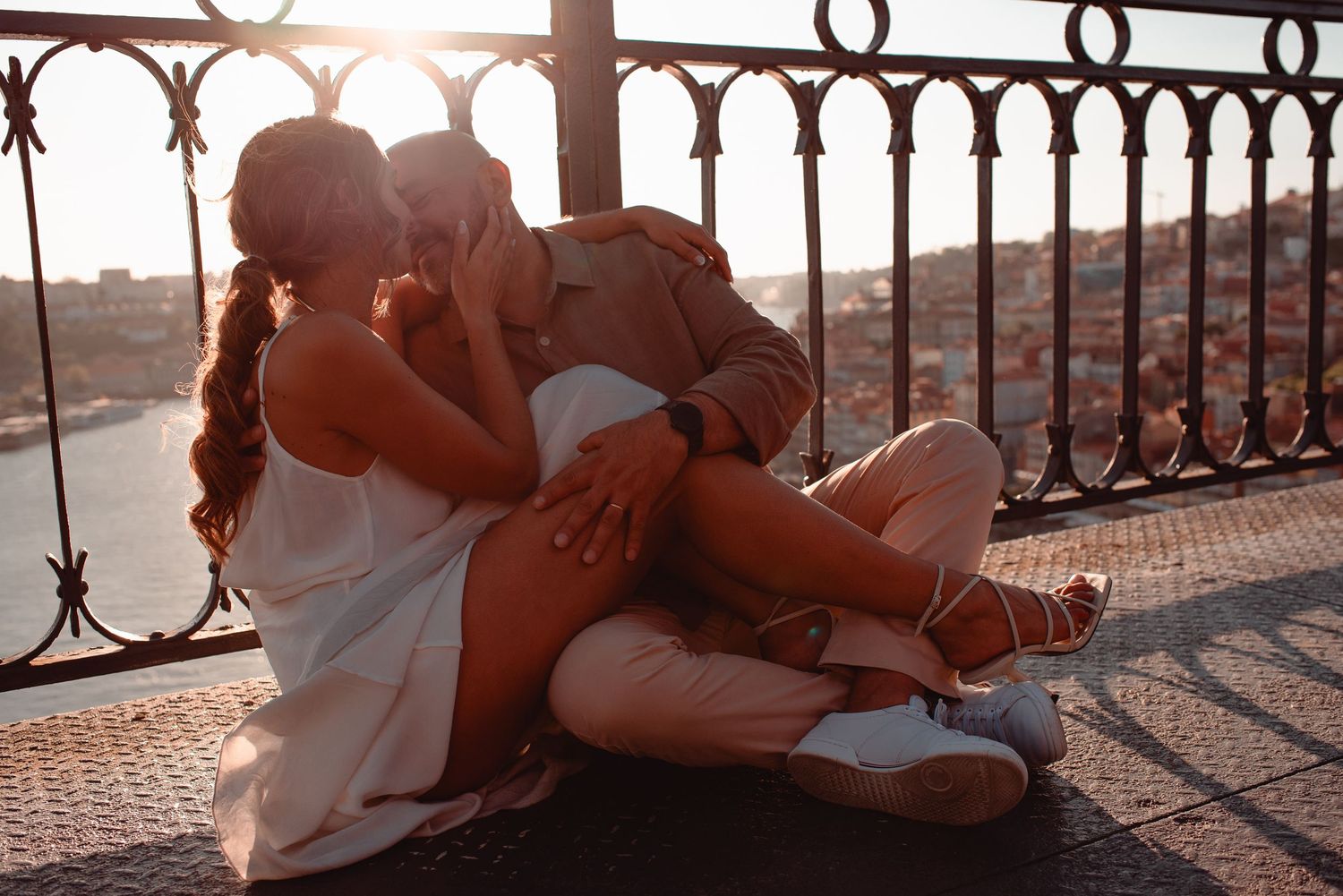 Romantic sunset scene through ornate iron railing with sun flare effects.
