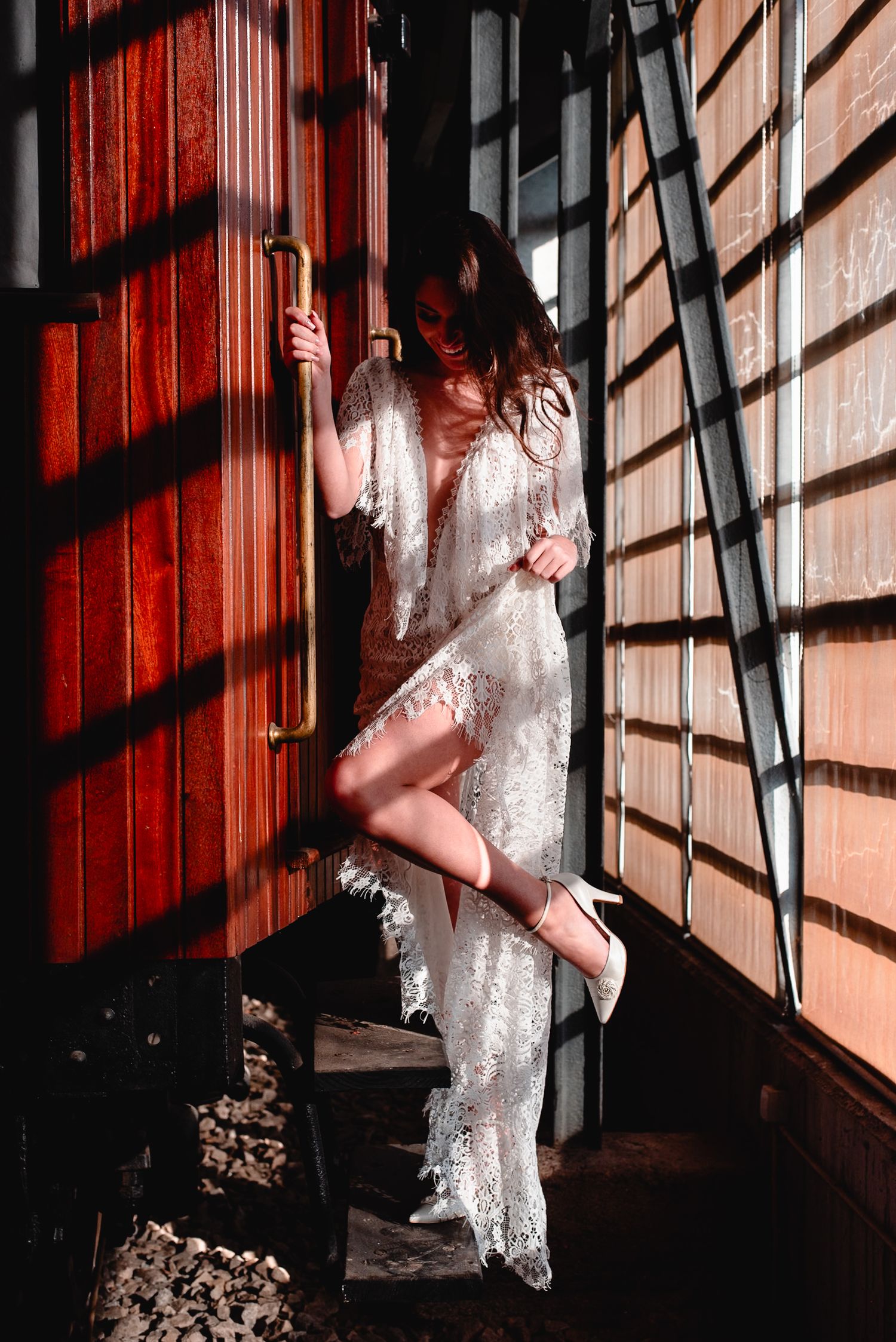 Artistic fashion photo showing white dress in dramatic shadows against vibrant red wooden wall.