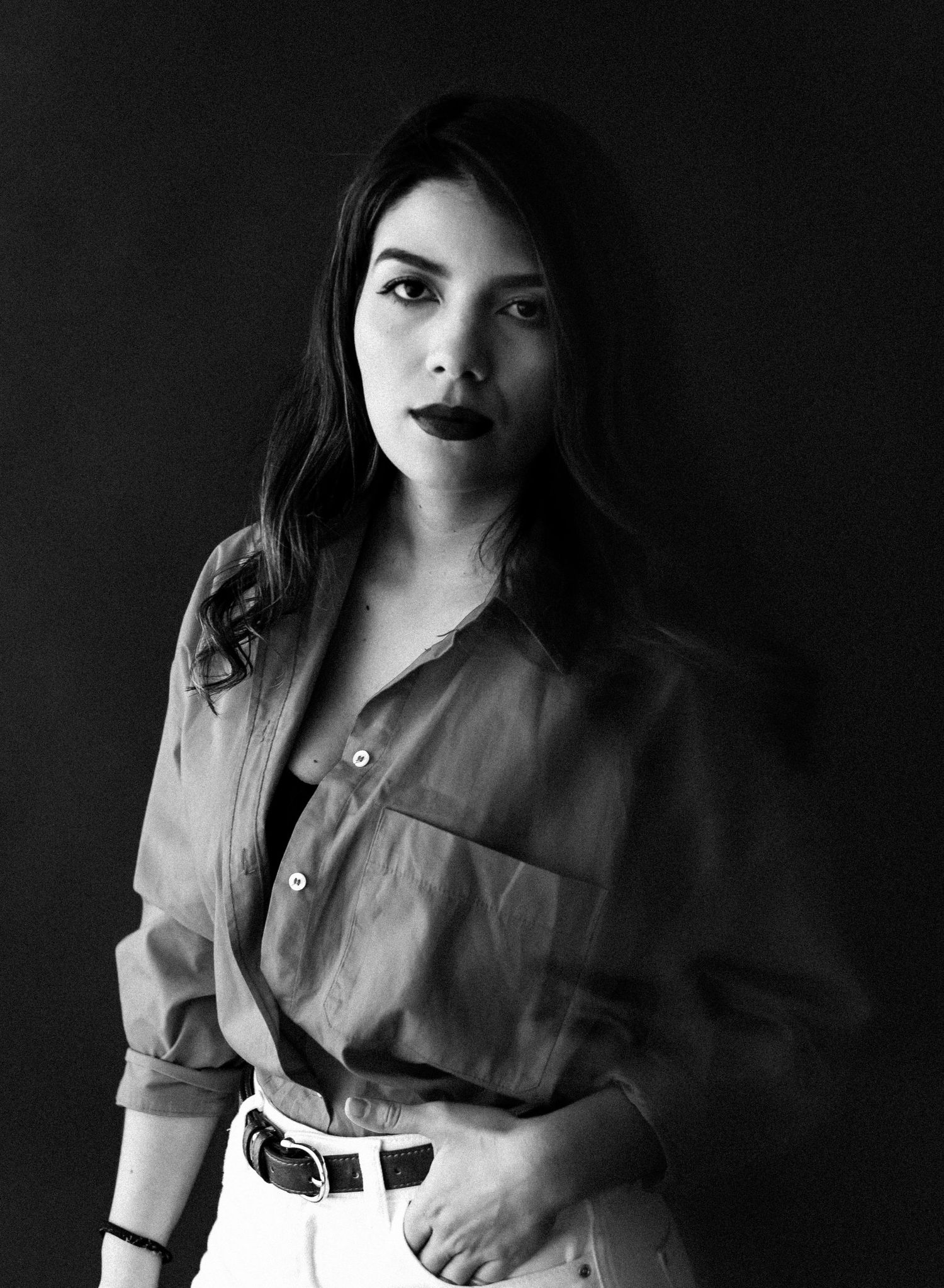 Dramatic black and white portrait in moody lighting against dark background.