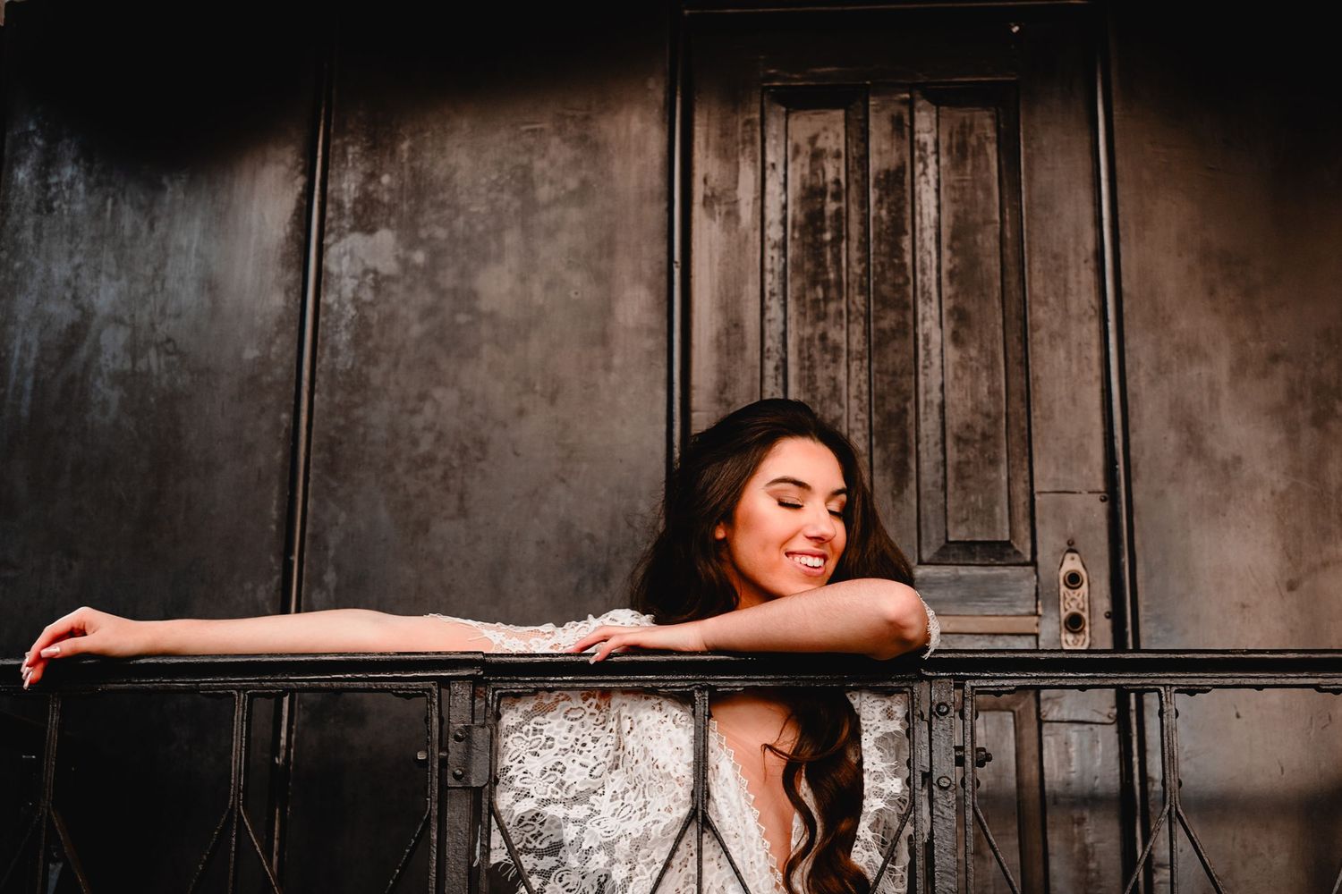 Dramatic pose with white lace dress against dark industrial backdrop.