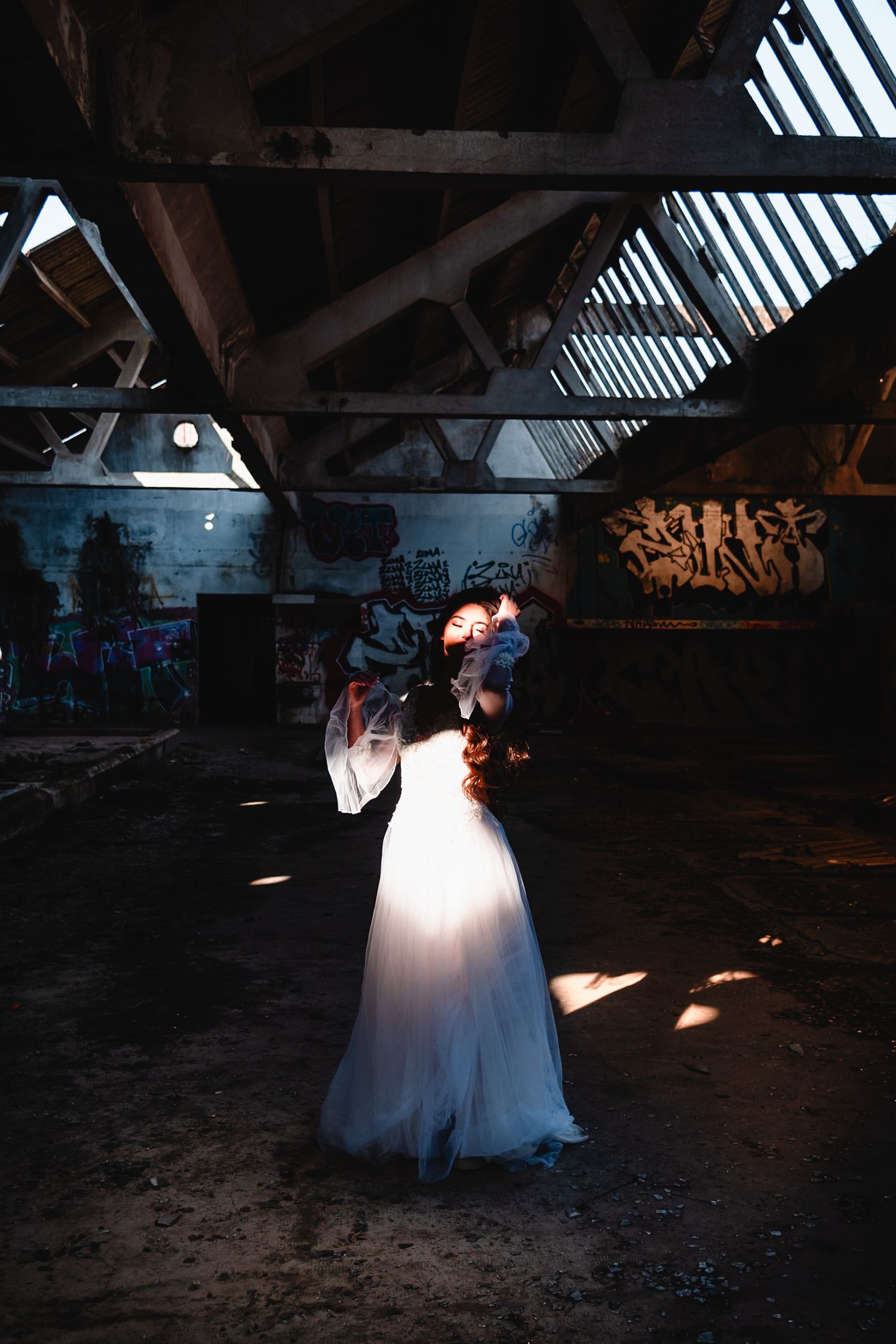 Dramatic wedding photography in a dark industrial space with streaks of natural light.