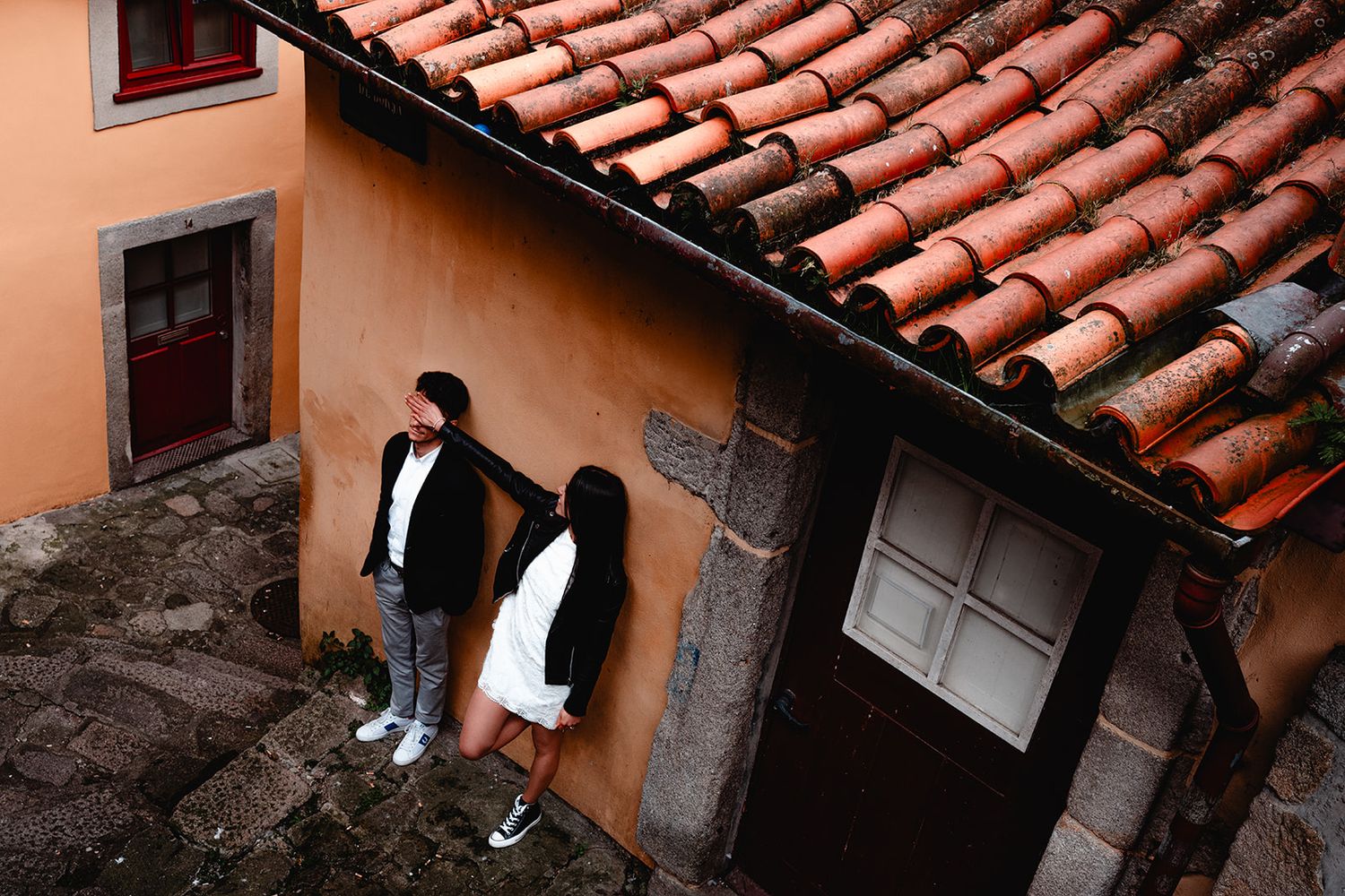 View of traditional terracotta tiled roofs and orange painted buildings from above.
