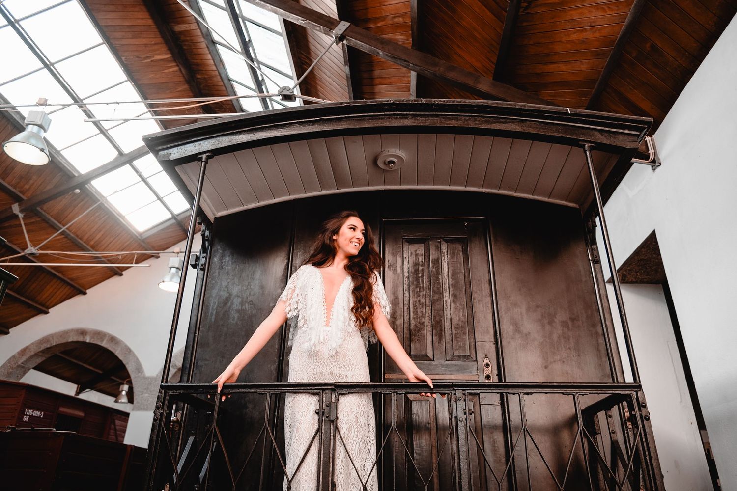 Artistic wide-angle shot of a white wedding dress in an industrial railway setting.