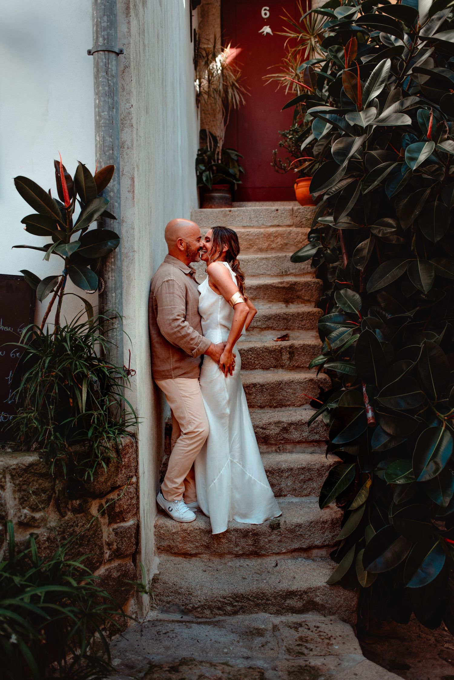 A romantic moment captured on rustic stone steps surrounded by lush green plants.