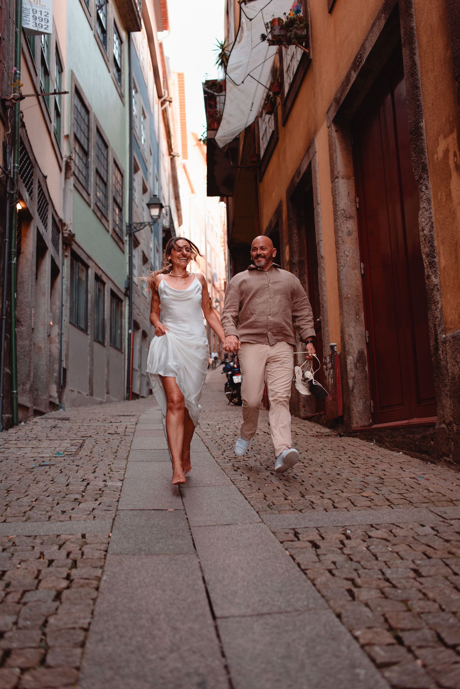 A couple strolling hand in hand through a charming narrow European street.