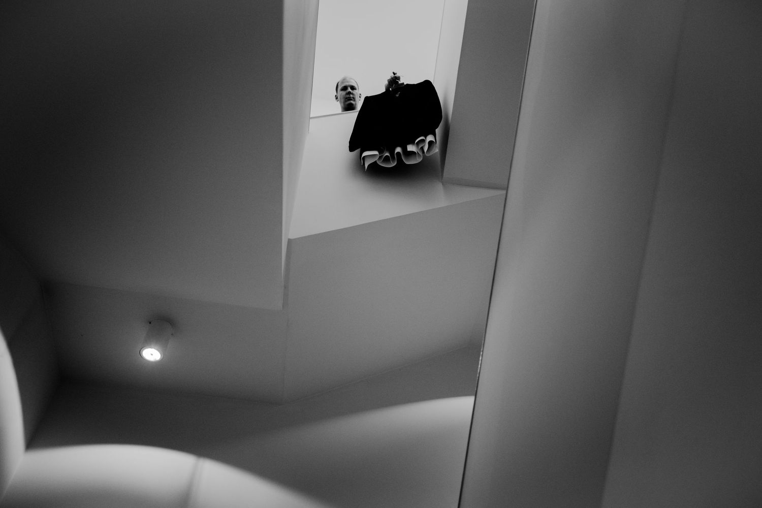 Black and white architectural interior with geometric shapes, a small figurine, and dramatic light contrast on white walls.