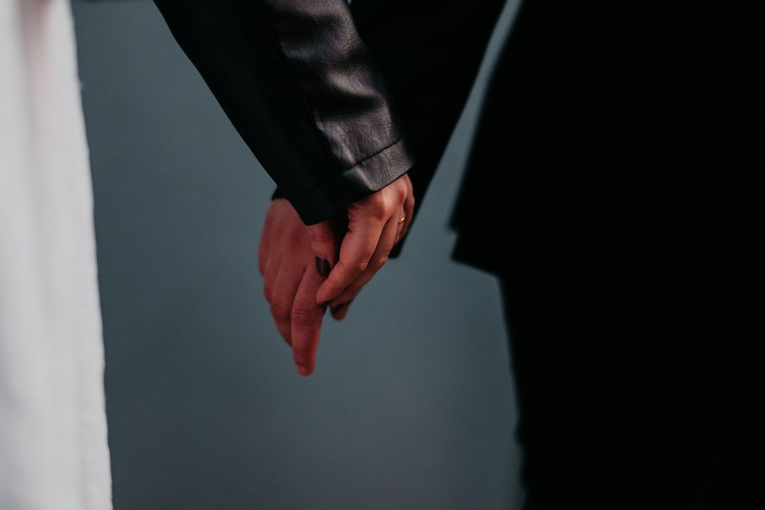 Close-up of two people holding hands tenderly, symbolizing love and connection against a dark background.