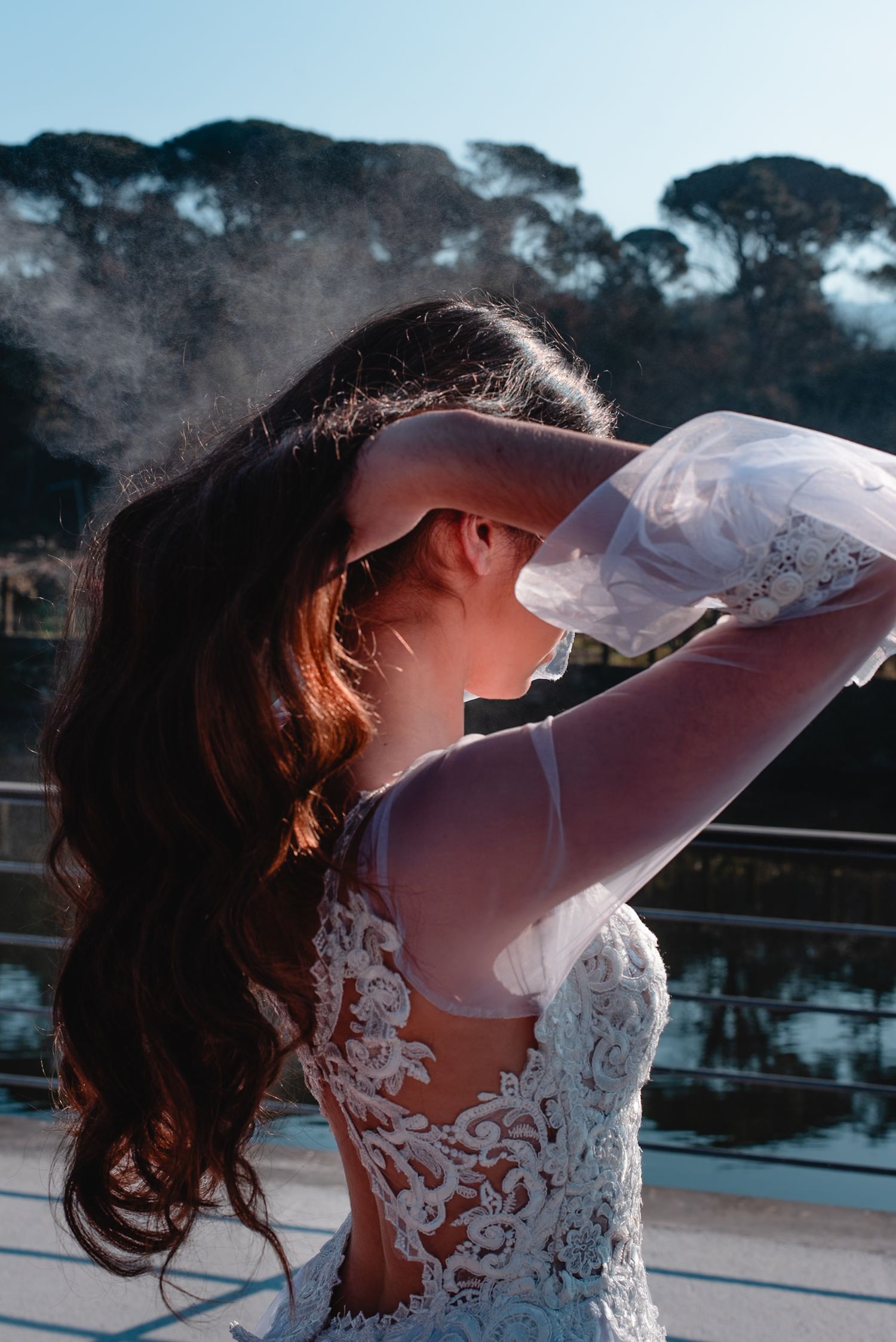 Ethereal bridal portraits showcasing intricate lace details of a white wedding gown against a bright sky.
