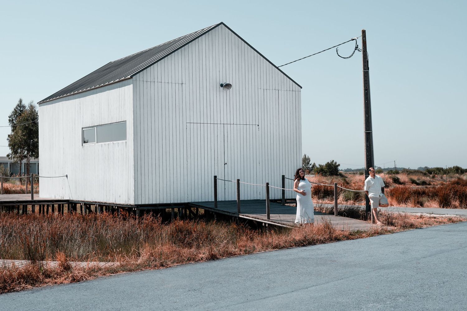Large white storage building with utility pole beside rural road.