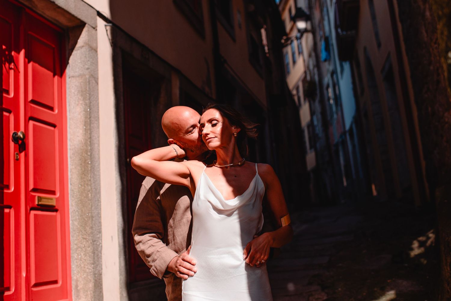 A romantic moment captured in an ancient stone corridor with dramatic lighting and red accents.