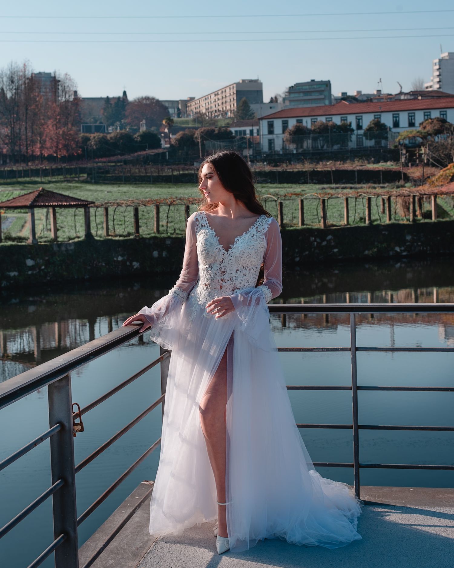 White wedding dress with lace details and flowing skirt photographed by riverside.