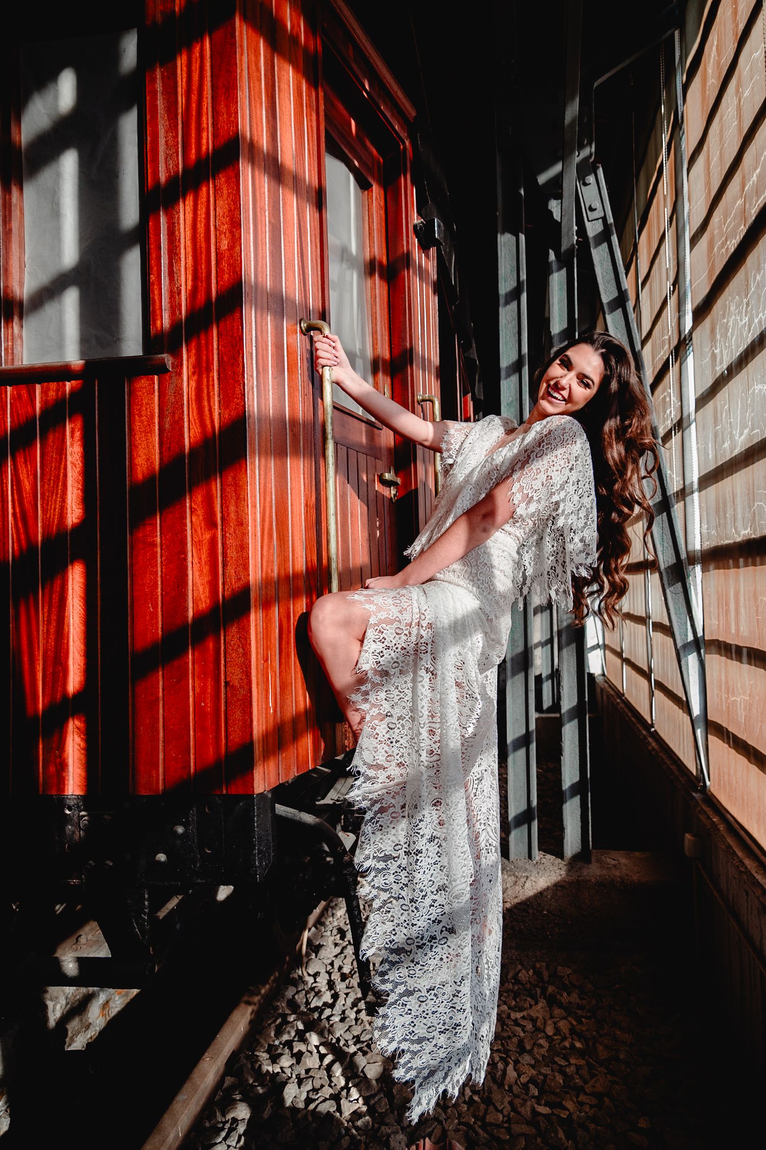 Fashion portrait with stark lighting contrasts and shadows against red wooden backdrop.