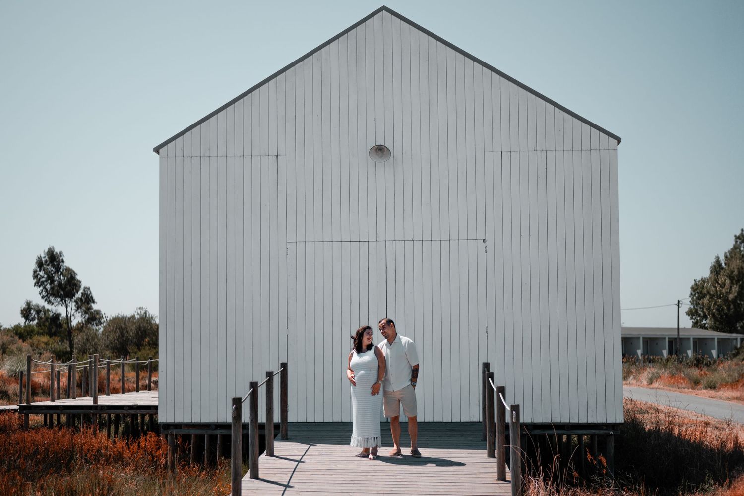 Modern white barn building serves as backdrop for outdoor photo session.