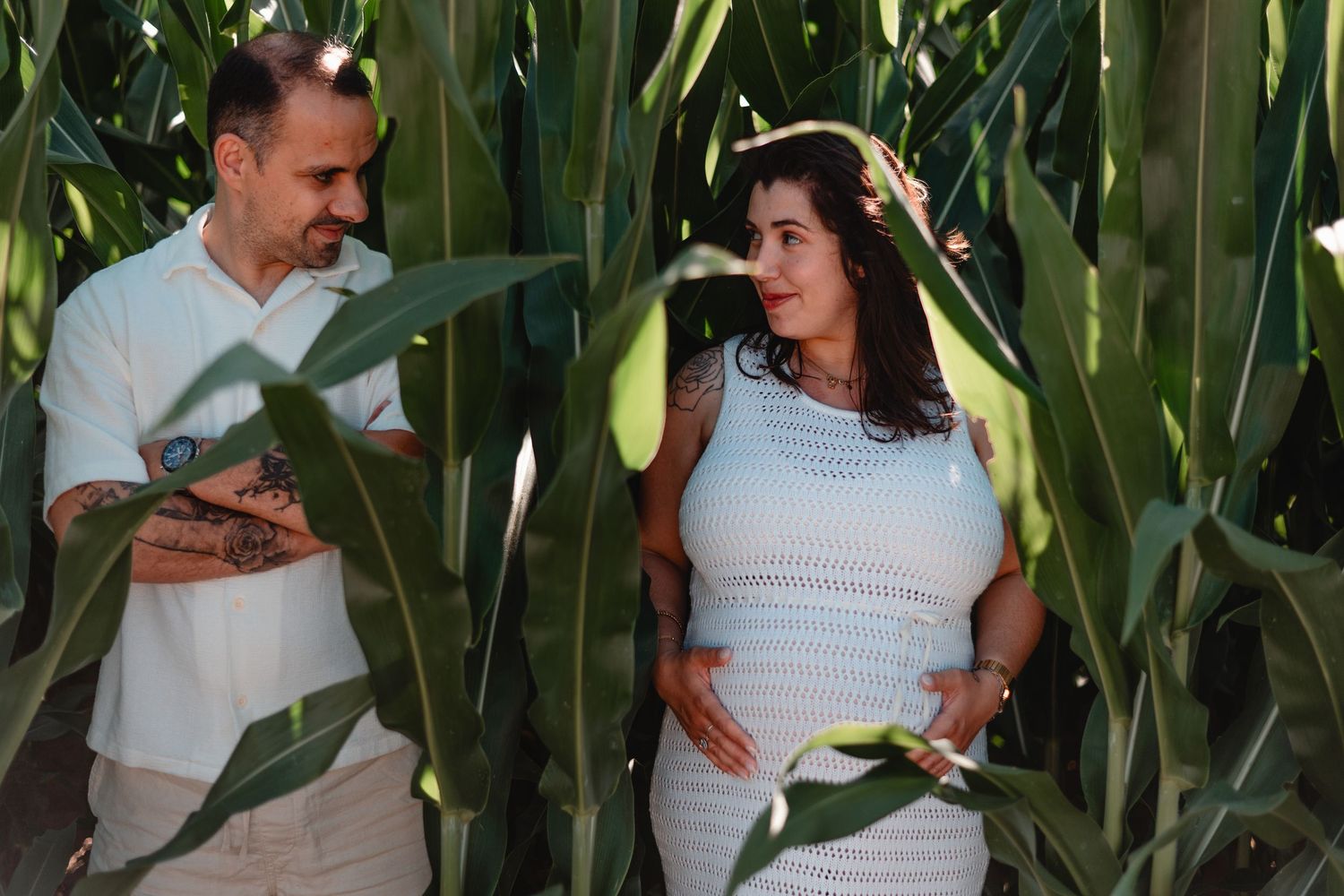 People pose among tall green corn stalks in a summer field.